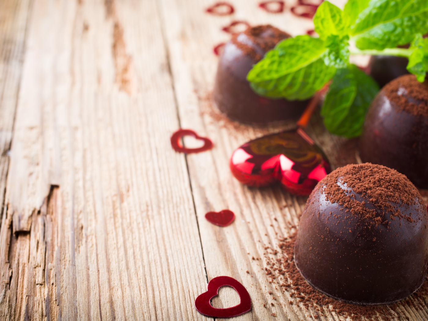 Шоколадные конфеты с какао на столе с мятой и сердечками
