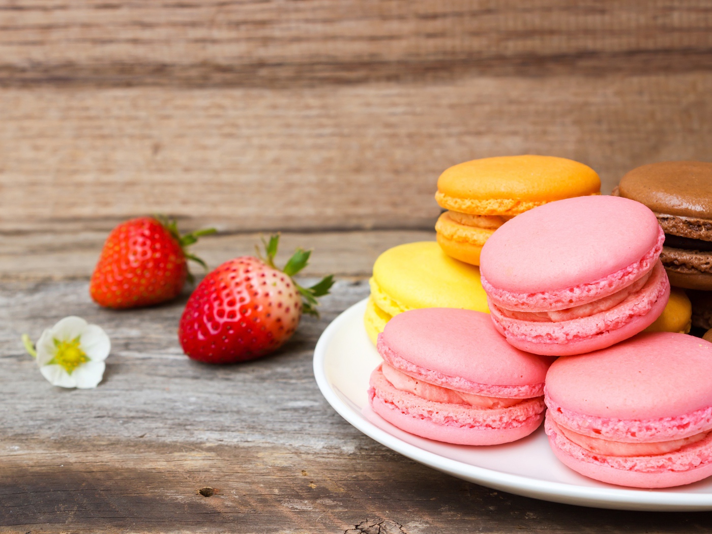 Разноцветный десерт макарун на столе с клубникой