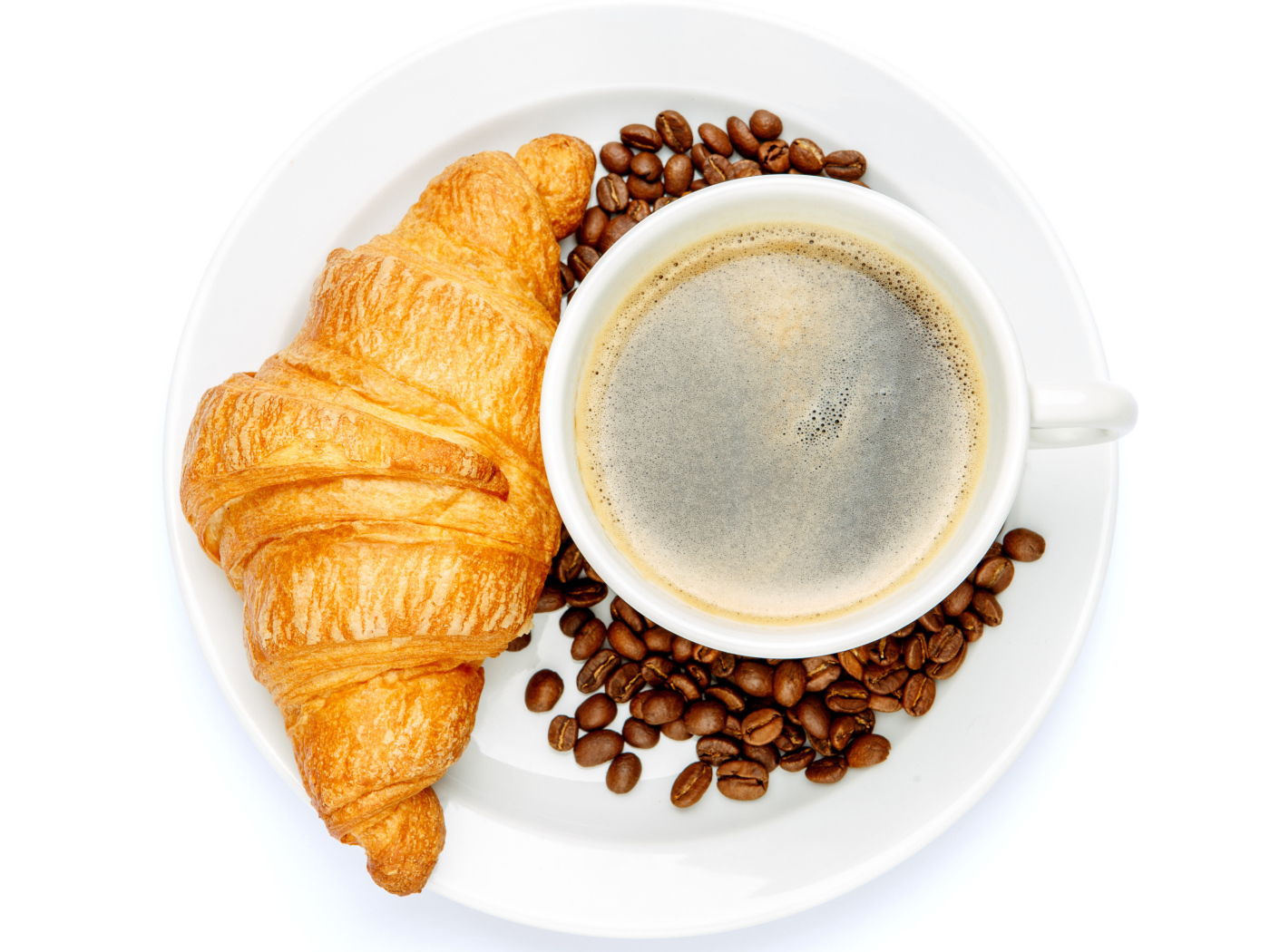 Чашка кофе на белой тарелке с круассаном и зернами, вид сверху 