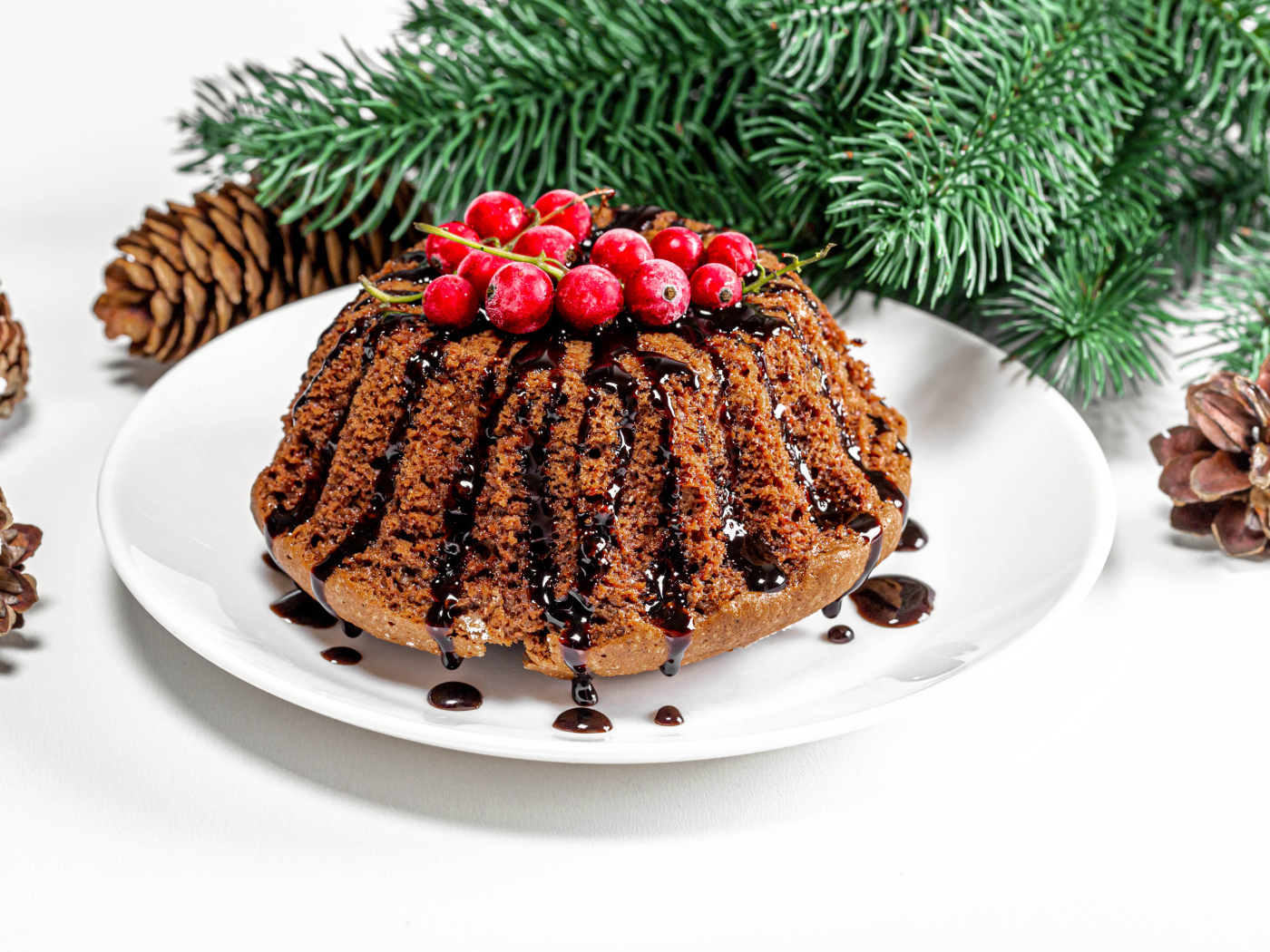 Вкусный кекс с шоколадом и красной смородиной на столе с еловой веткой и шишками