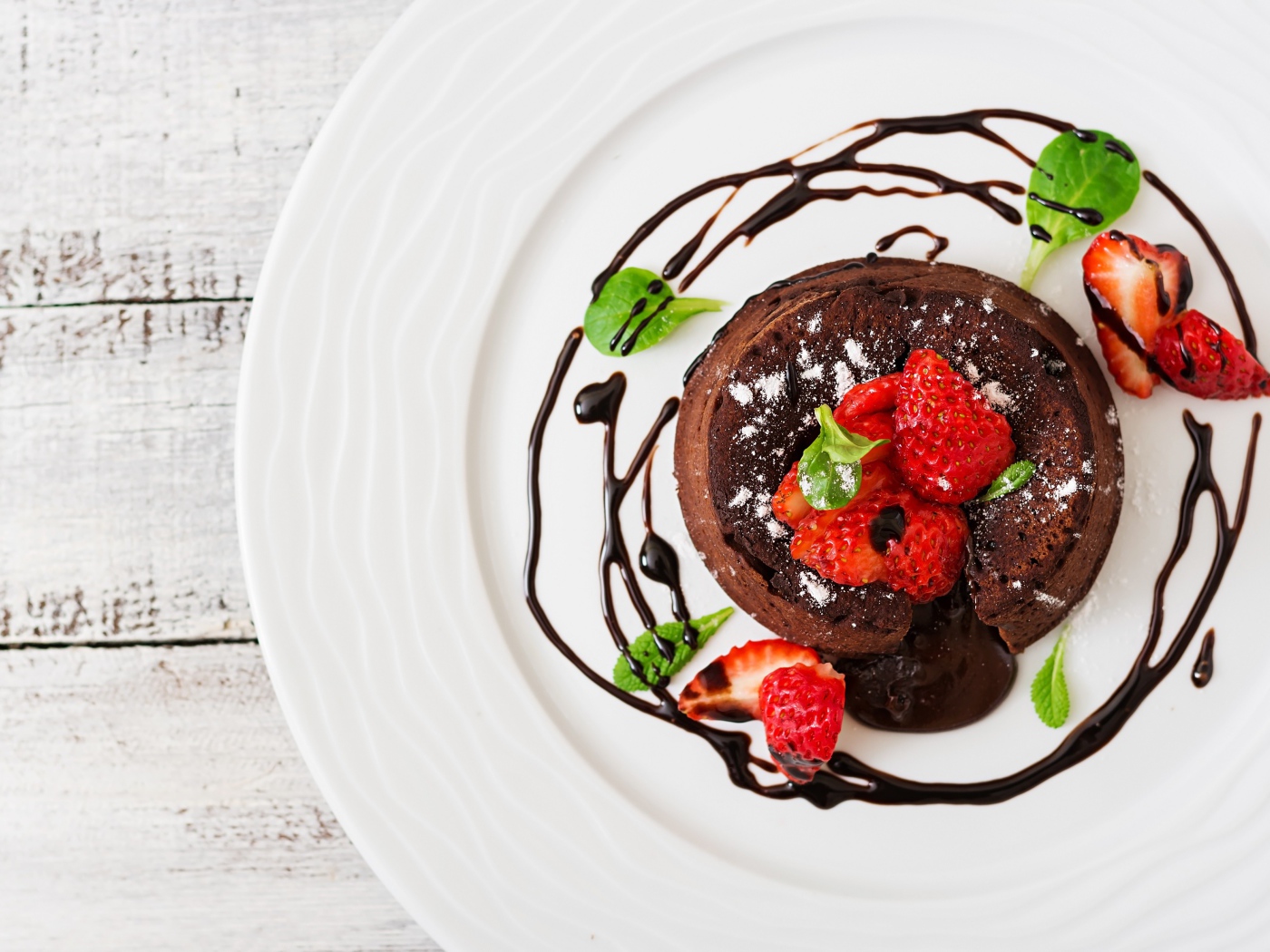 Вкусный десерт на белой тарелке с клубникой и шоколадом