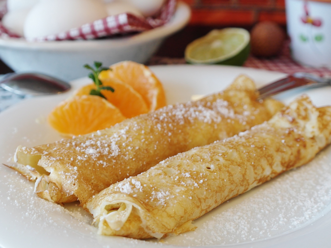 Блины с сахарной пудрой на тарелке с дольками мандарина