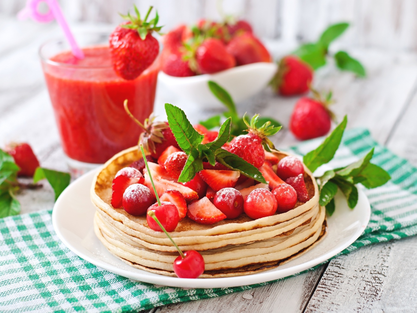 Блины с ягодами клубники  и черешни на белой тарелке