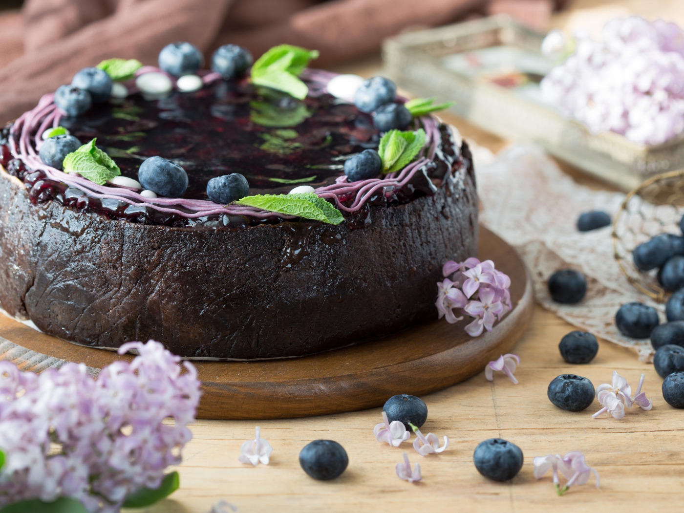 Пирог с джемом и ягодами черники на столе с сиренью 
