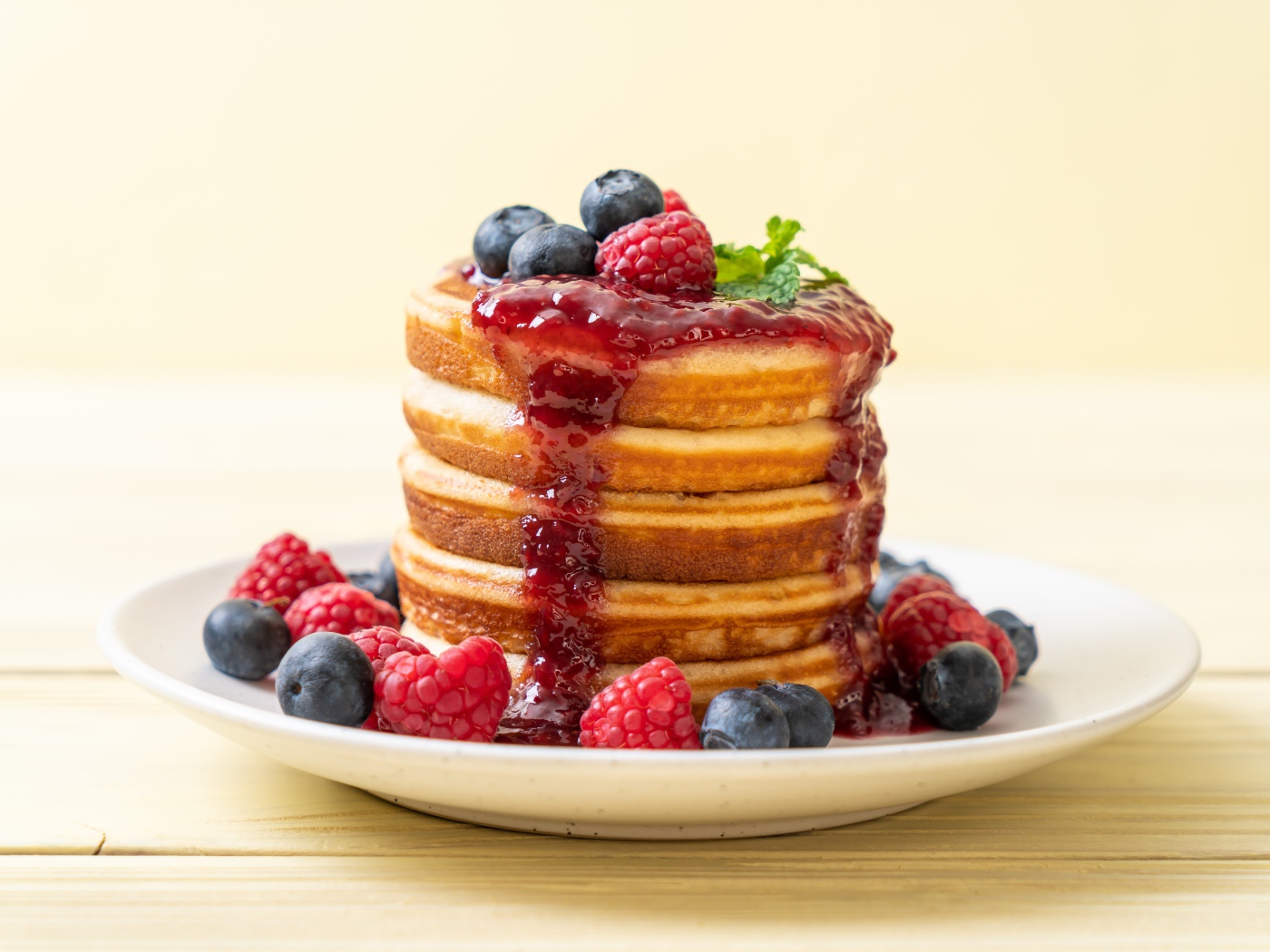 Румяные панкейки с джемом и ягодами черники и малины на тарелке