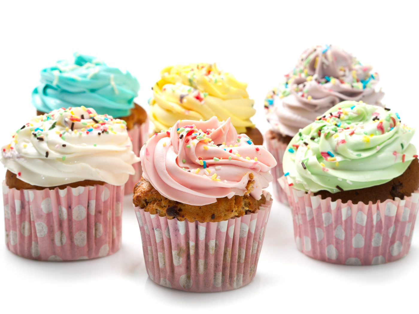 Сладкие кексы с кремом и посыпкой на белом фоне