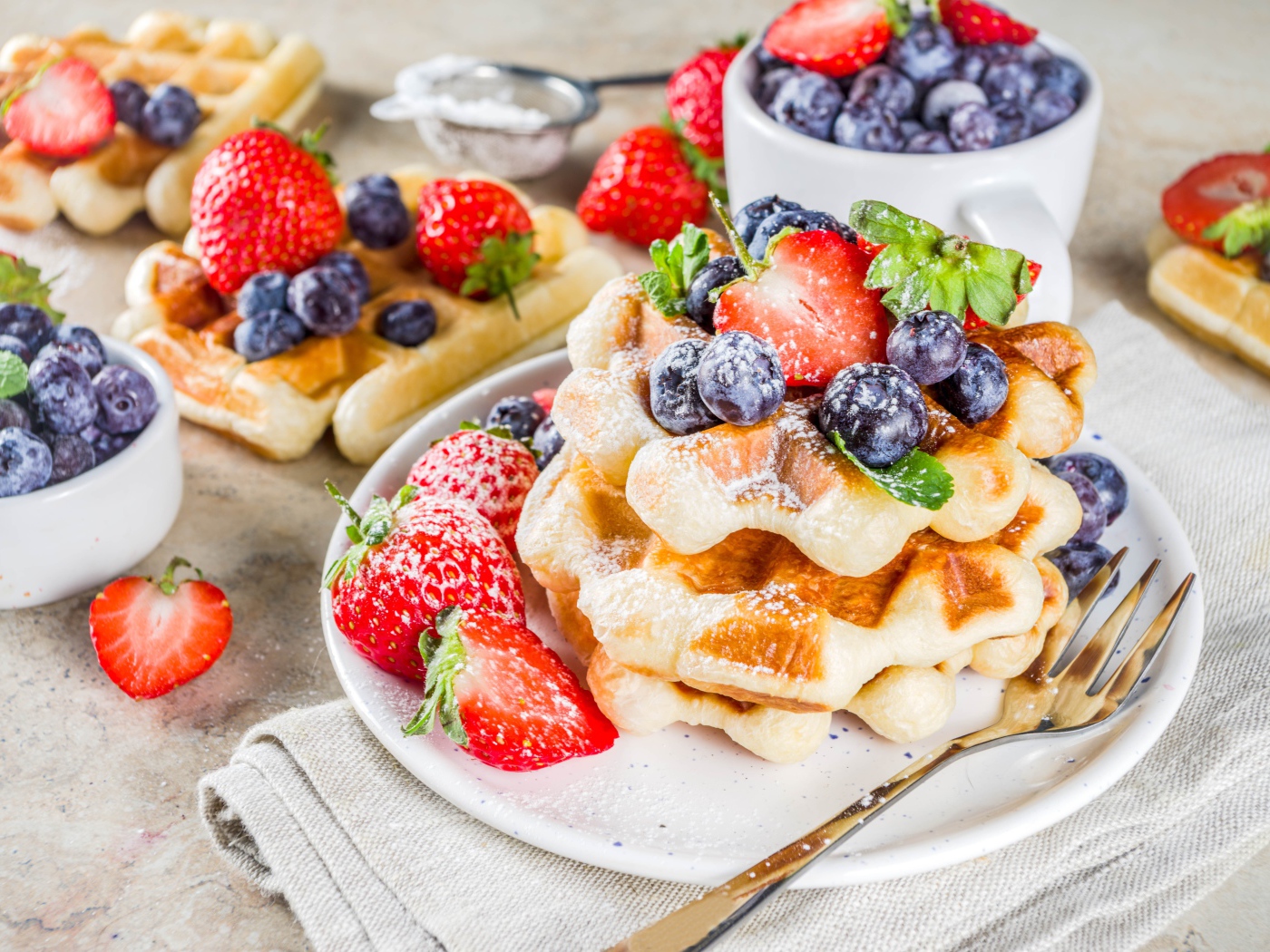 Вкусные сладкие вафли с ягодами клубники, черники и сахарной пудрой