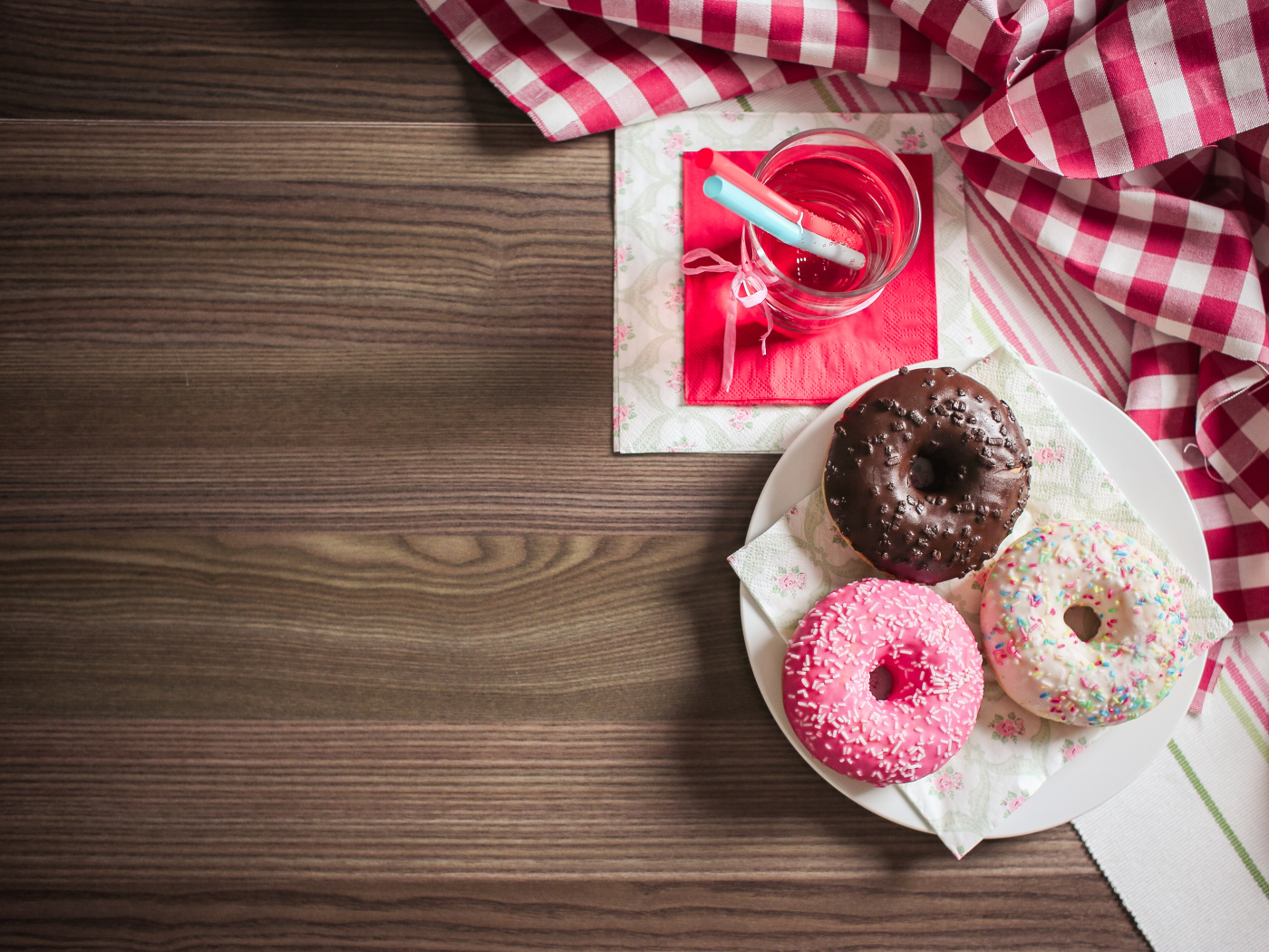 Три сладких пончика с глазурью на столе с лимонадом