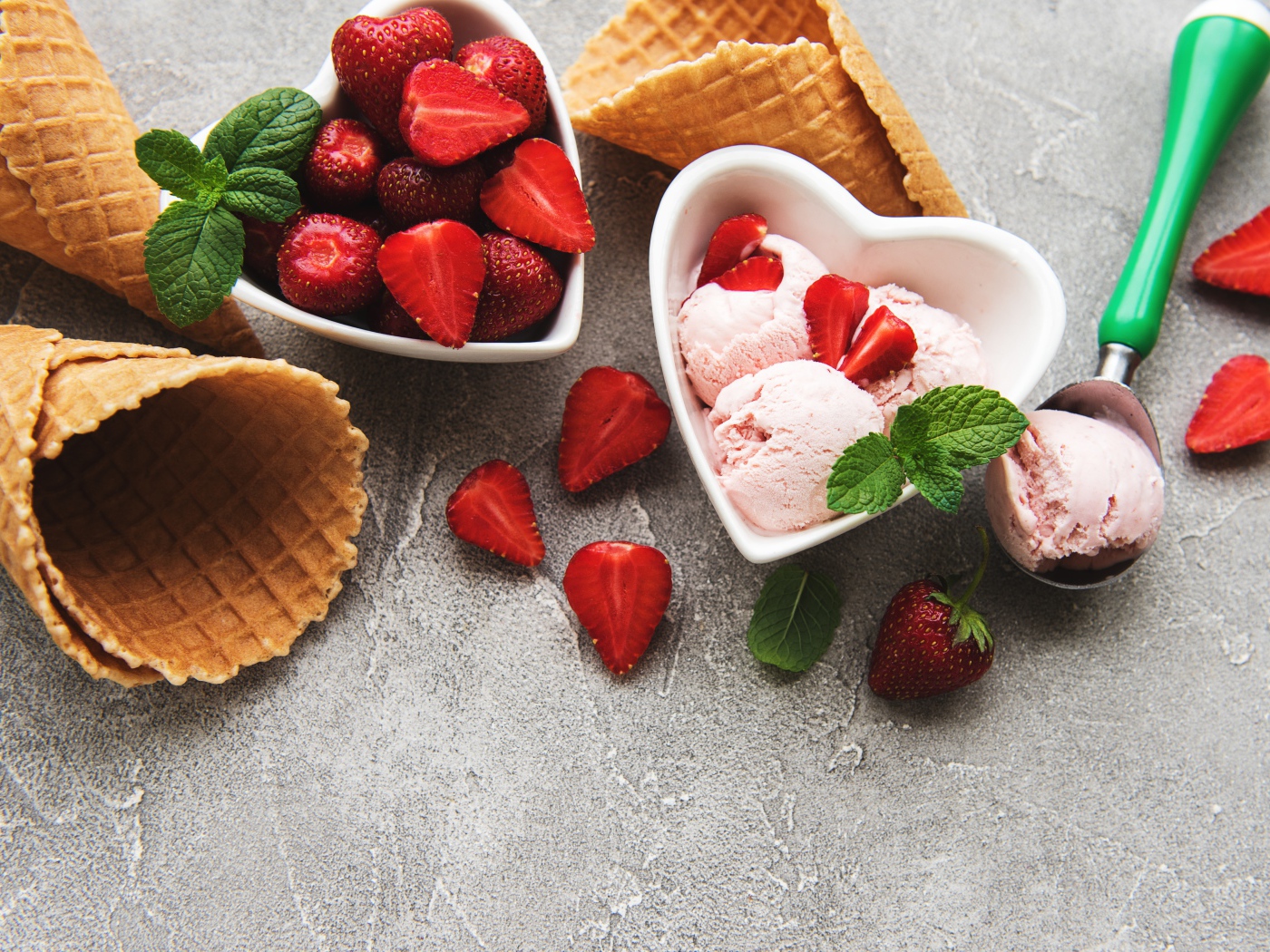 Вафельные рожки на столе с фруктовым мороженым и ягодами клубники 