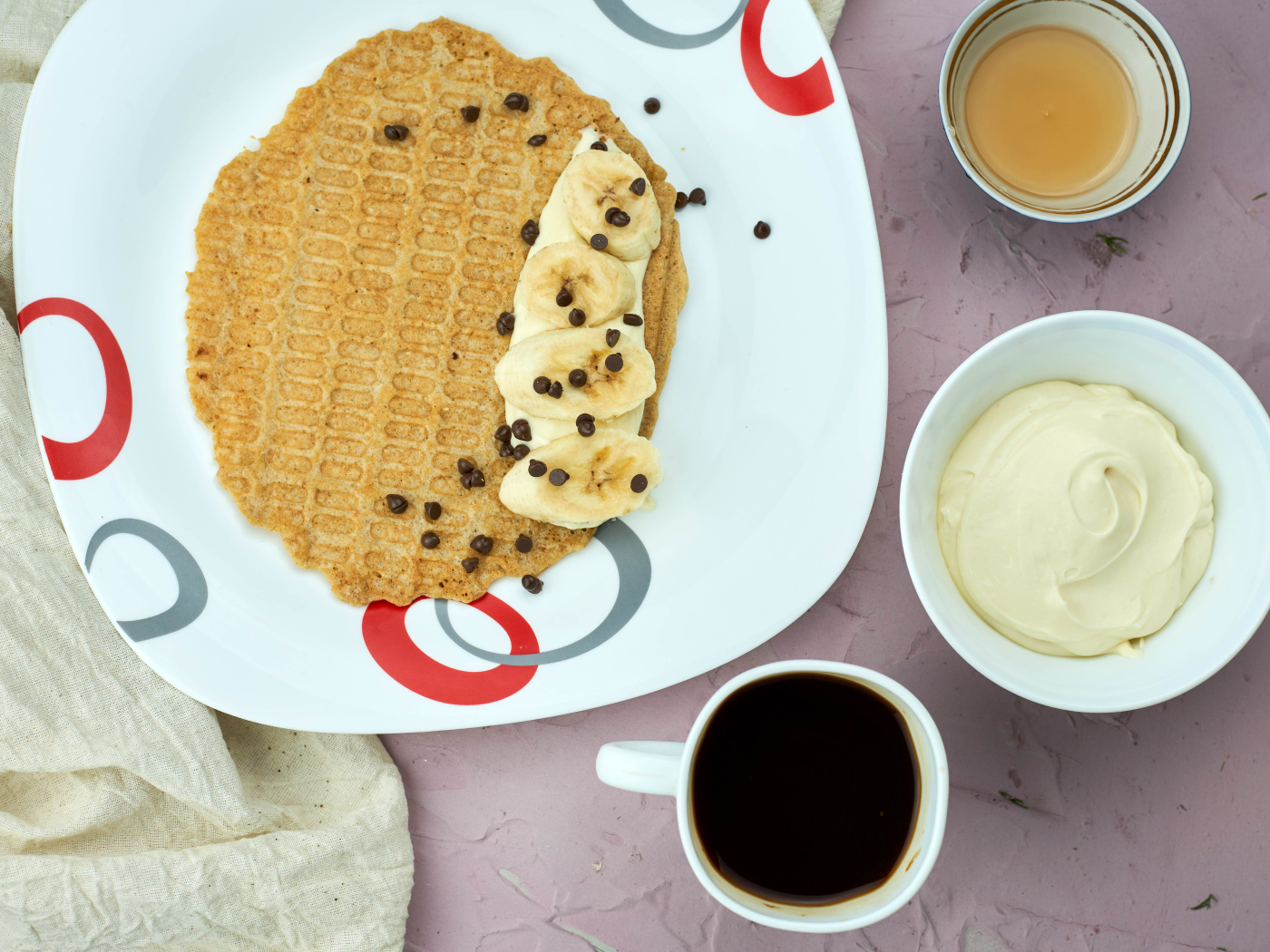 Вафля с бананами на столе с кофе и сметаной 