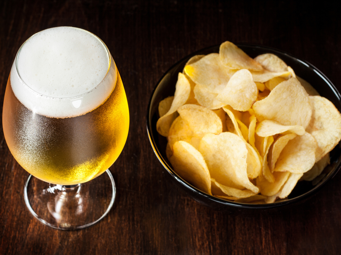 Миска с чипсами на столе с бокалом пива 