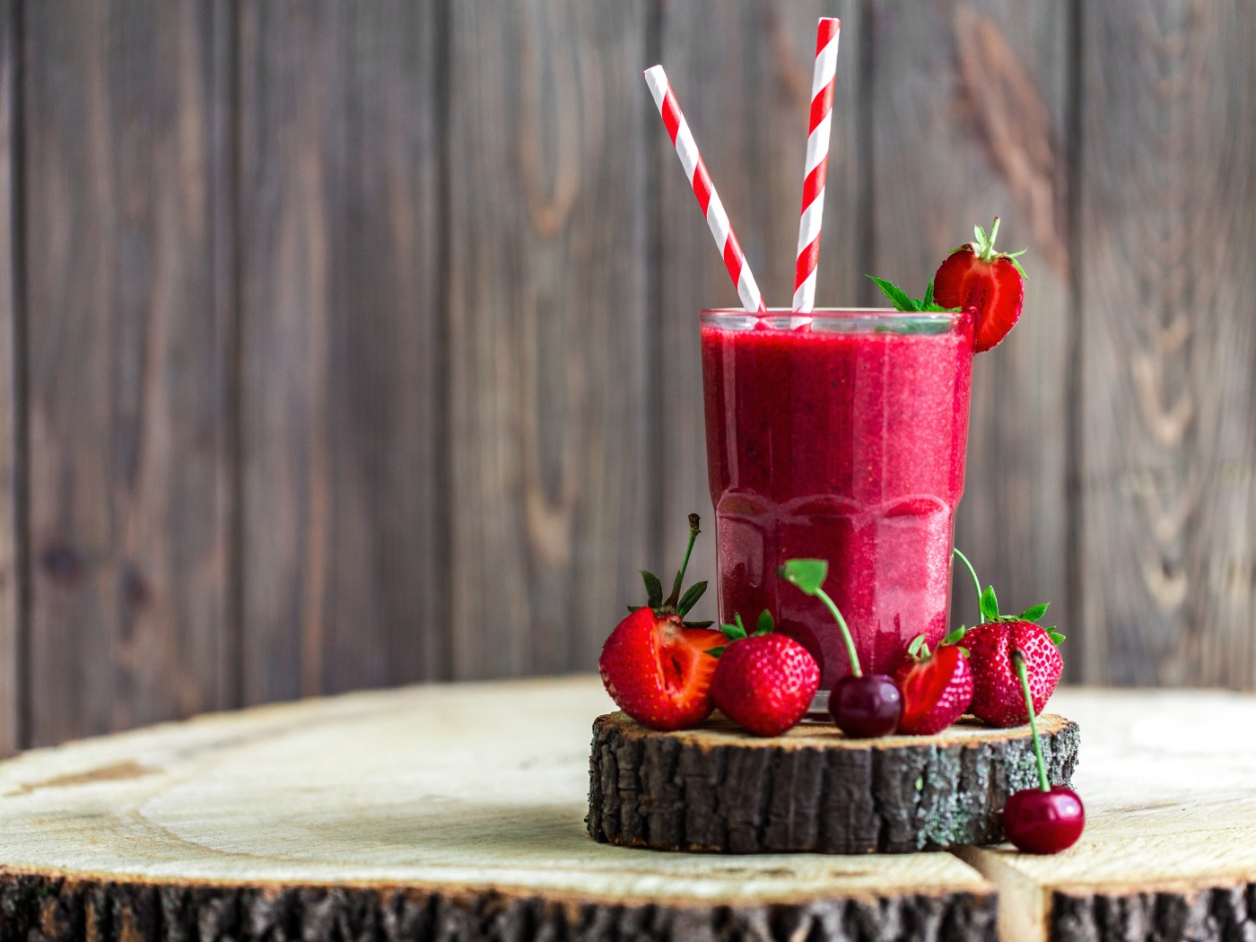 Стакан ягодного смузи на столе с клубникой и вишней