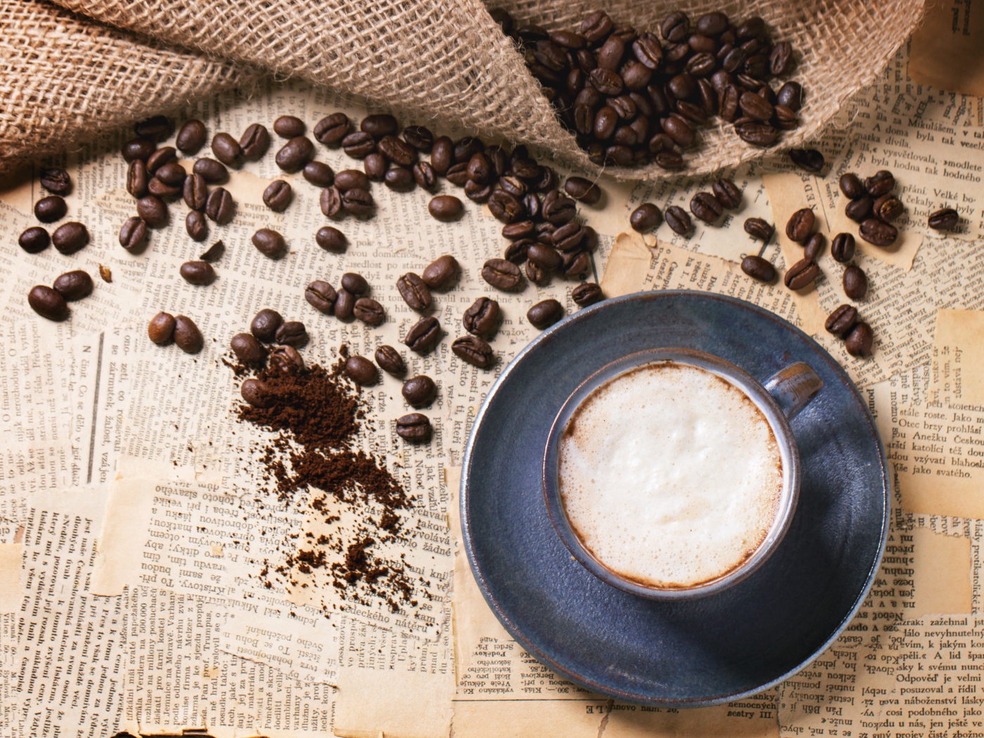 Чашка кофе на столе со старыми газетами и зернами