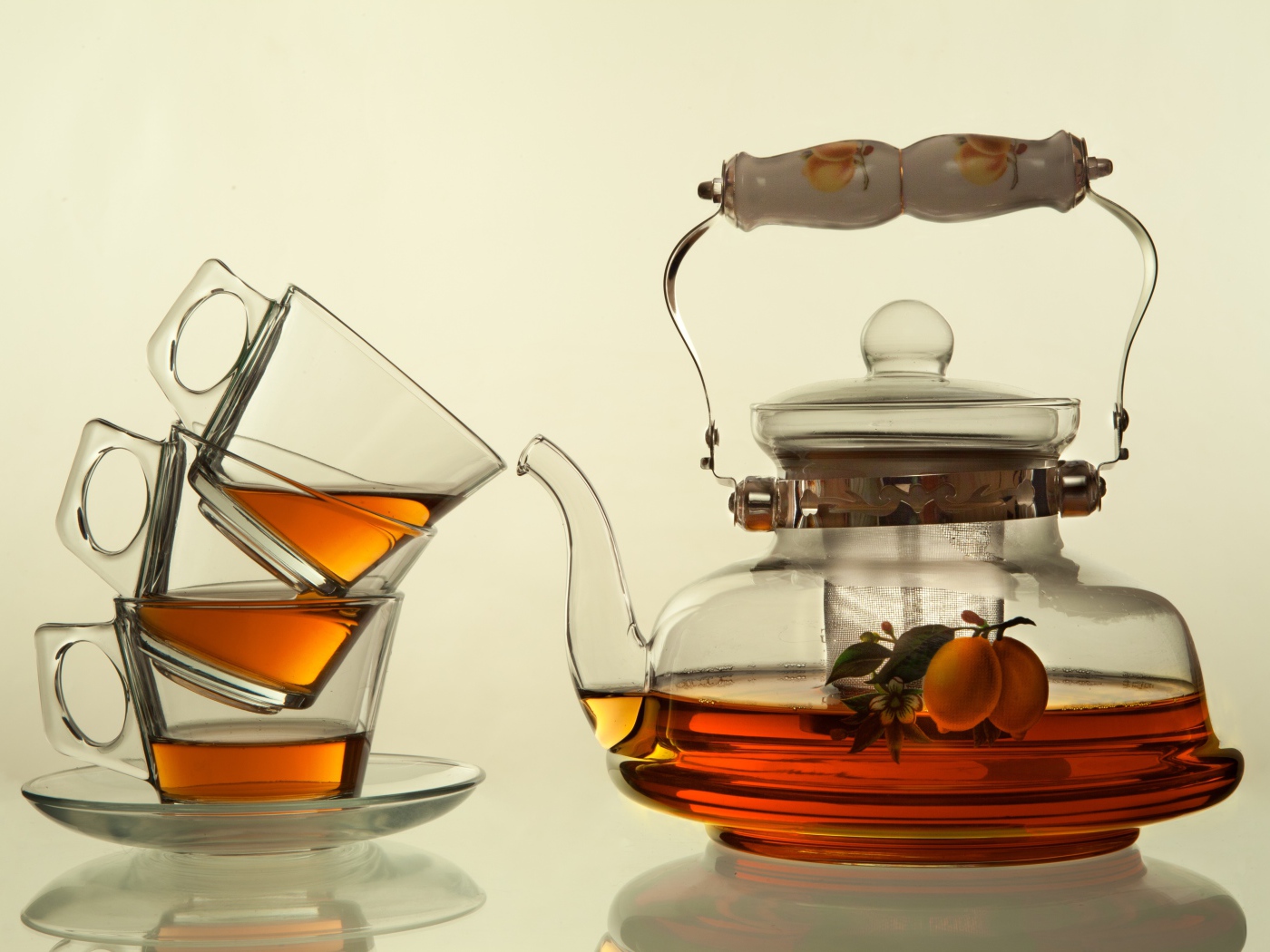 Стеклянный чайник с чашками на белом фоне