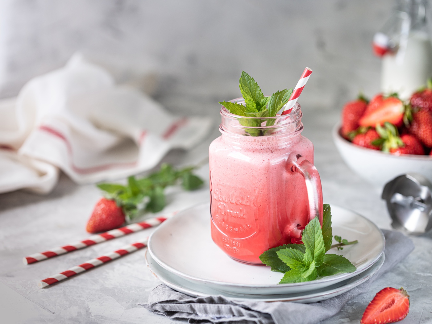 Смузи с клубникой в банке с трубочкой и листьями мяты