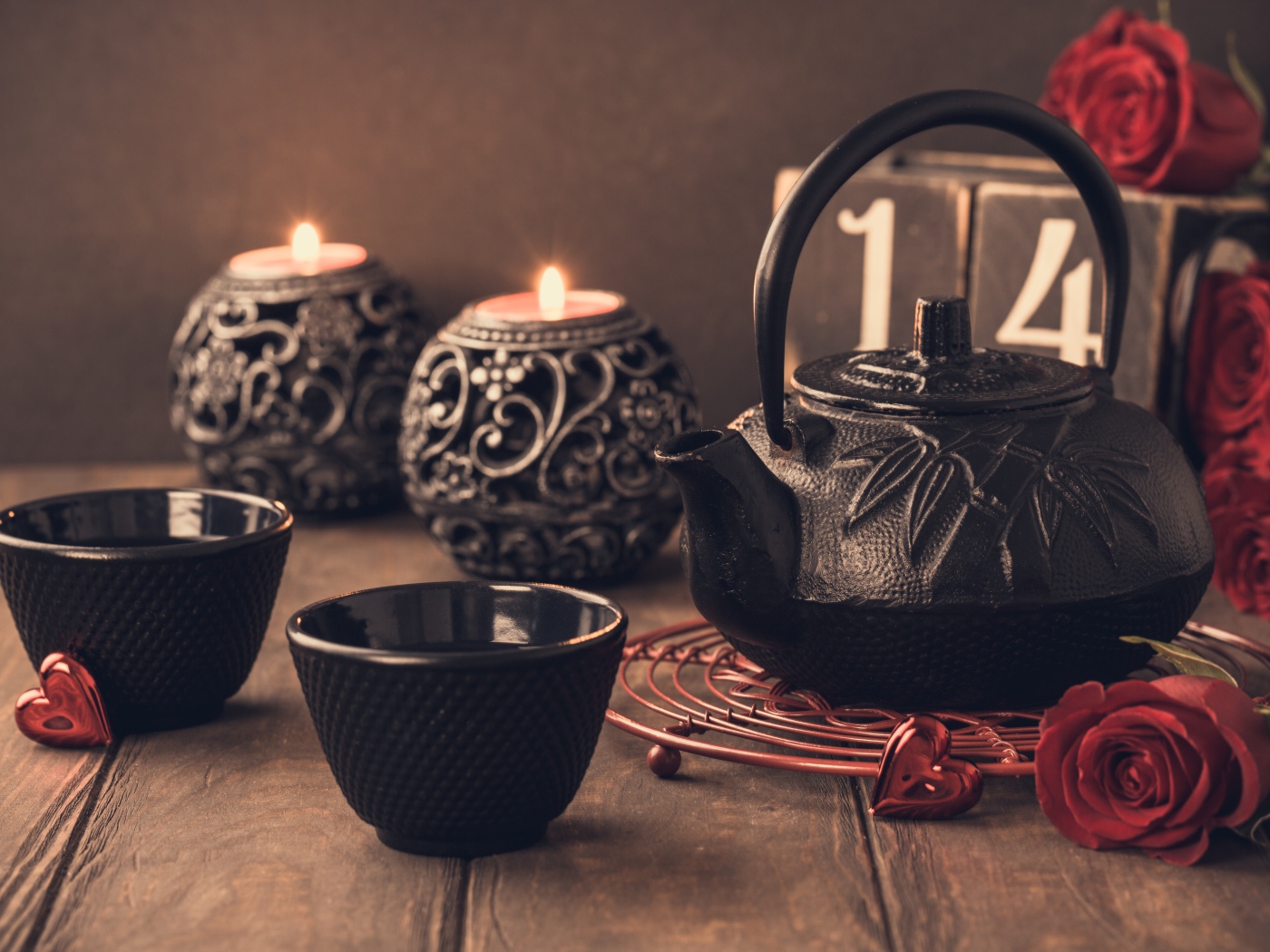 Две чашки чая на столе со свечами и красными розами