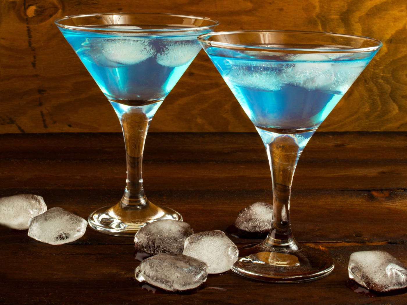 Два бокала коктейля на столе с кусочками льда