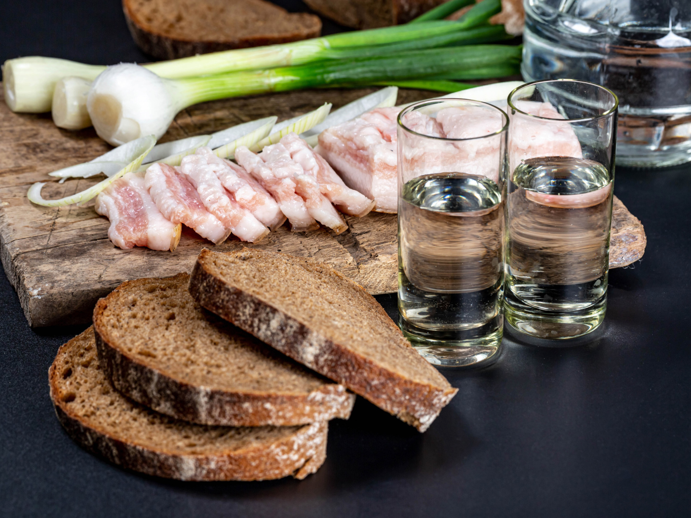 Две рюмки водки на столе с аппетитной закуской 