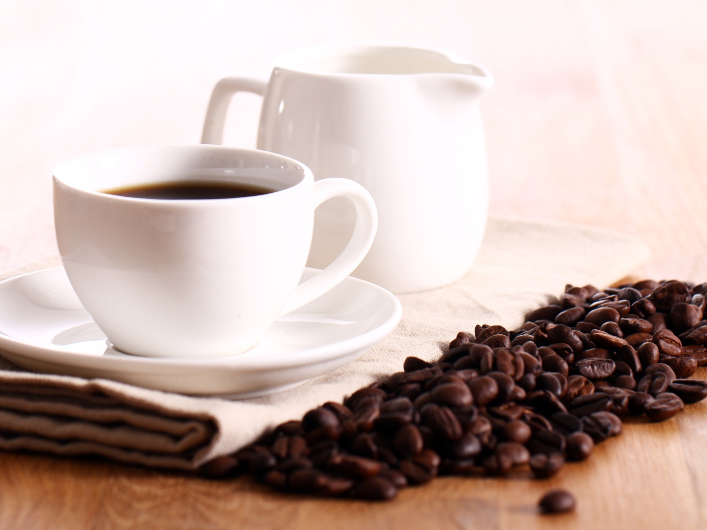 Белая чашка кофе на столе с молоком и зернами