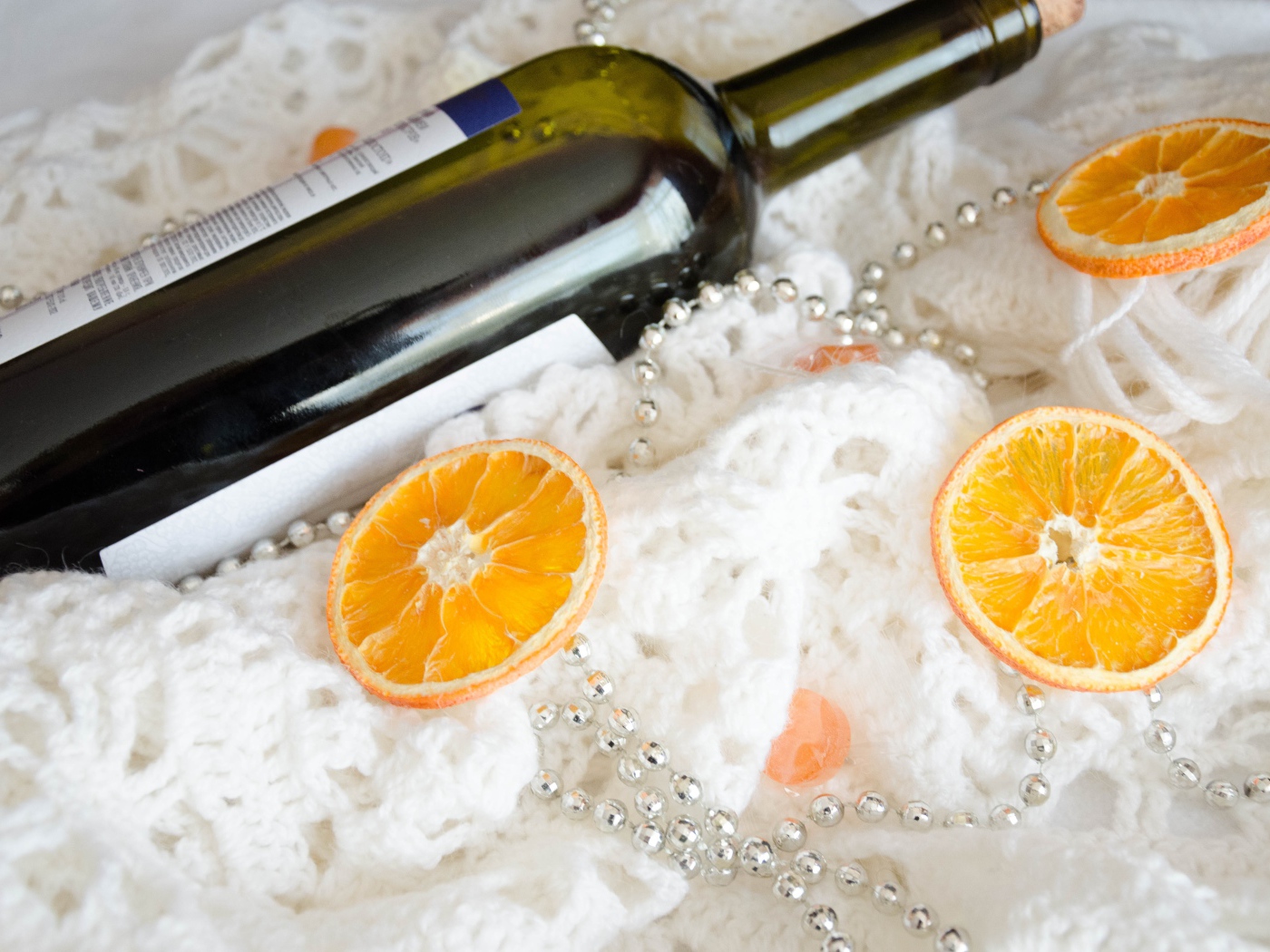 Бутылка вина и кусочки апельсина на белом платке 