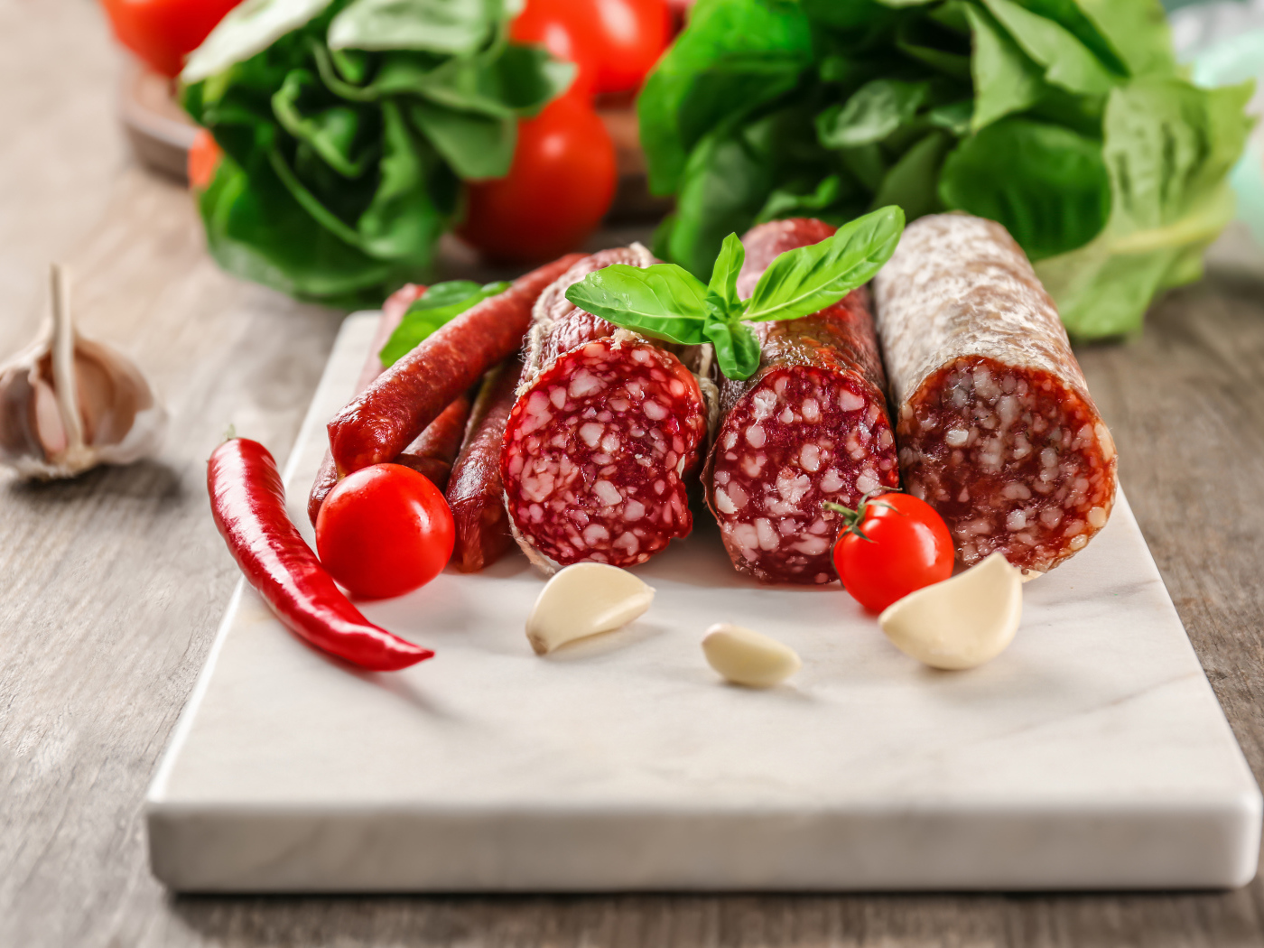 Вкусные колбасные изделия на столе с овощами