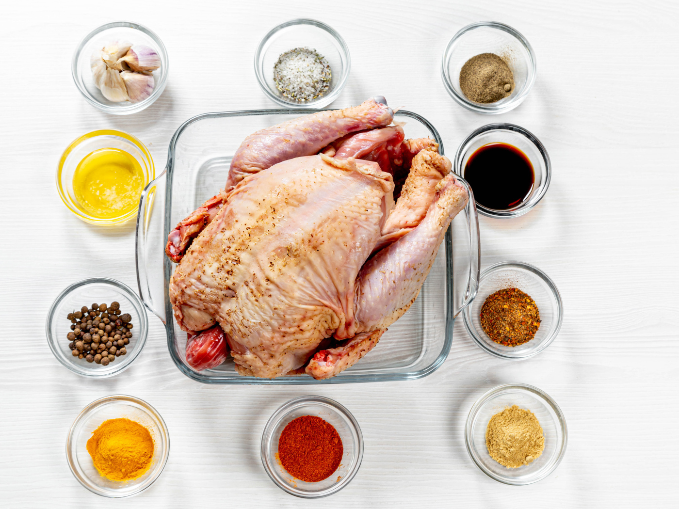Свежая курица на противне на столе со специями 