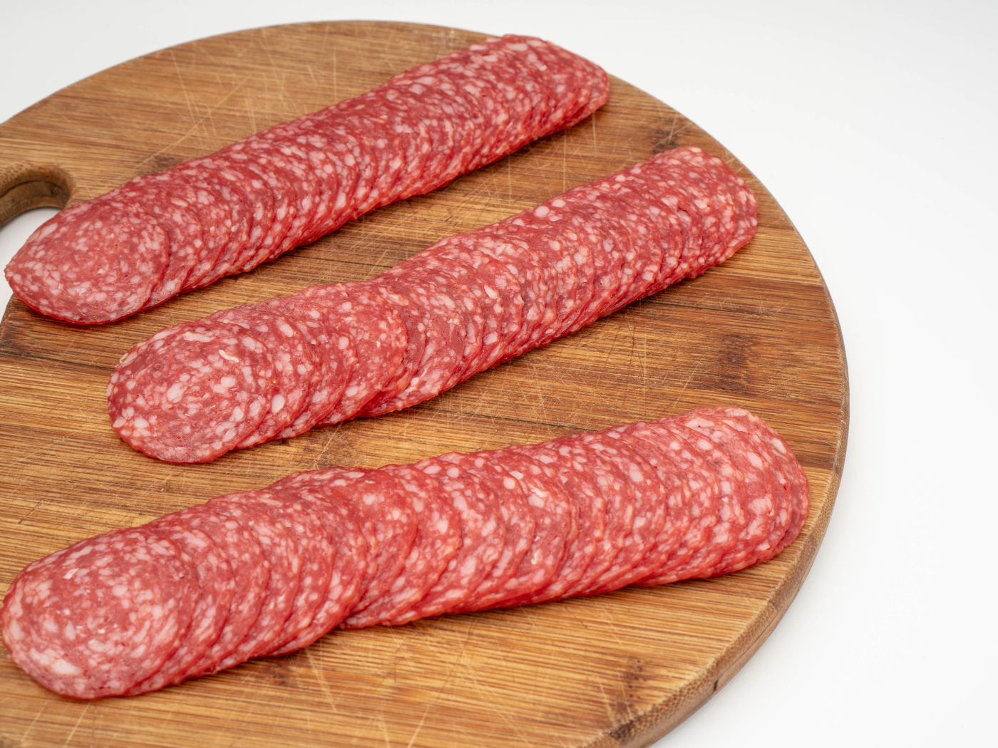 Колбаса тонко нарезана на разделочной доске 