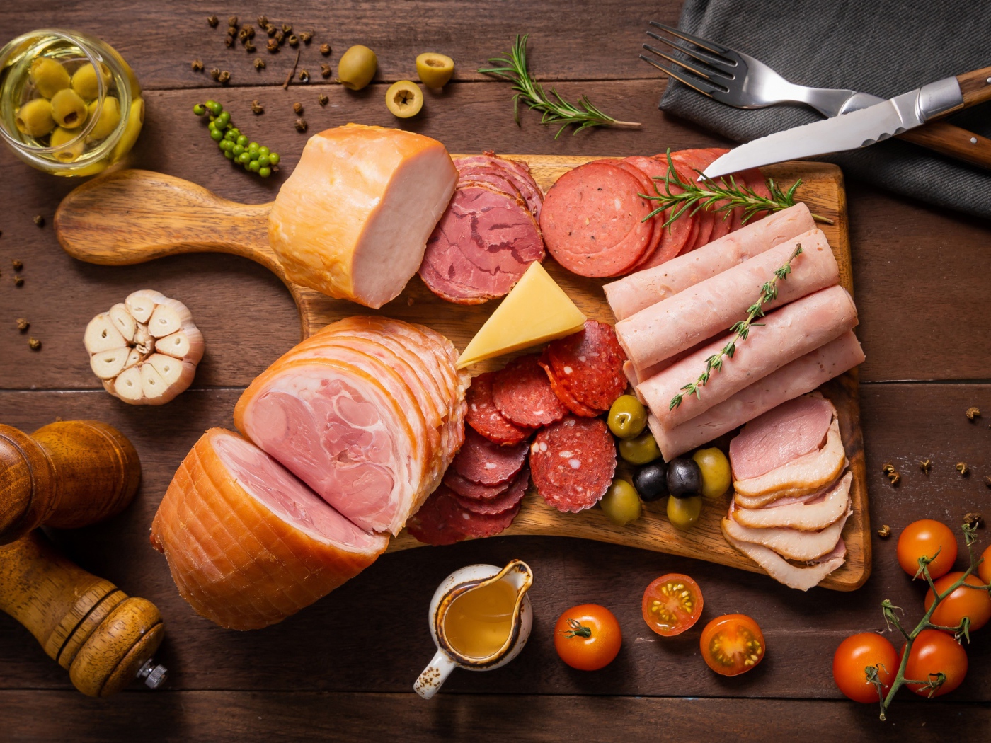 Колбасы и мясные продукты на доске со специями