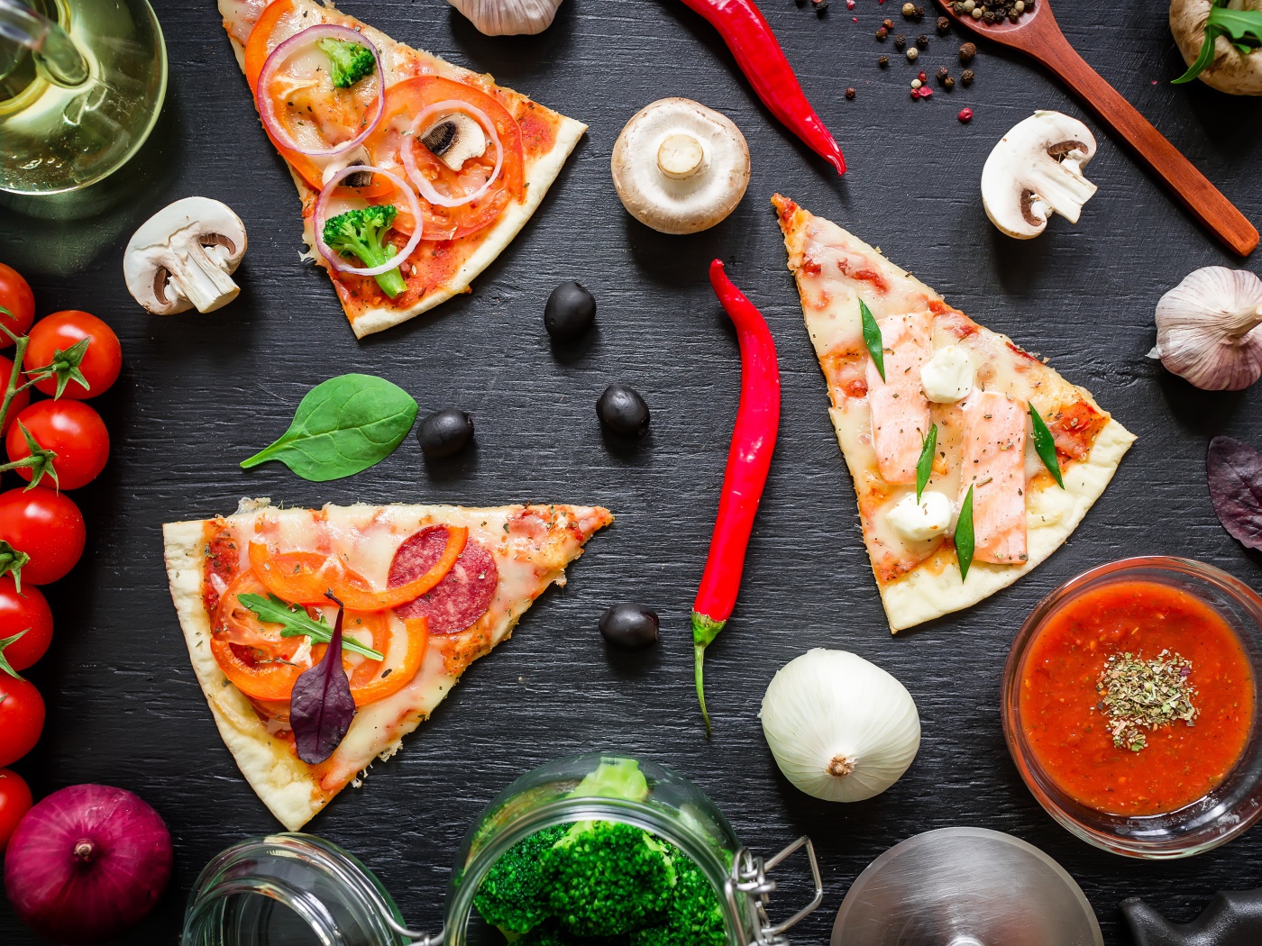 Куски пиццы на столе с овощами и соусом