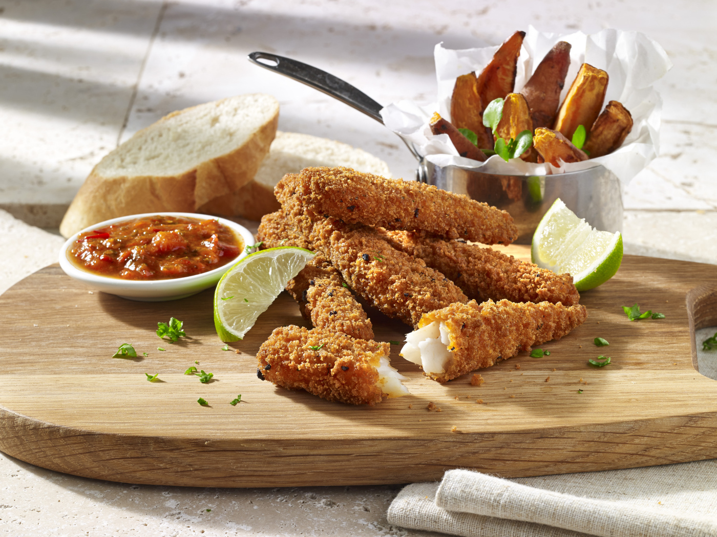 Рыба в панировке на столе с соусом и кусочками лайма