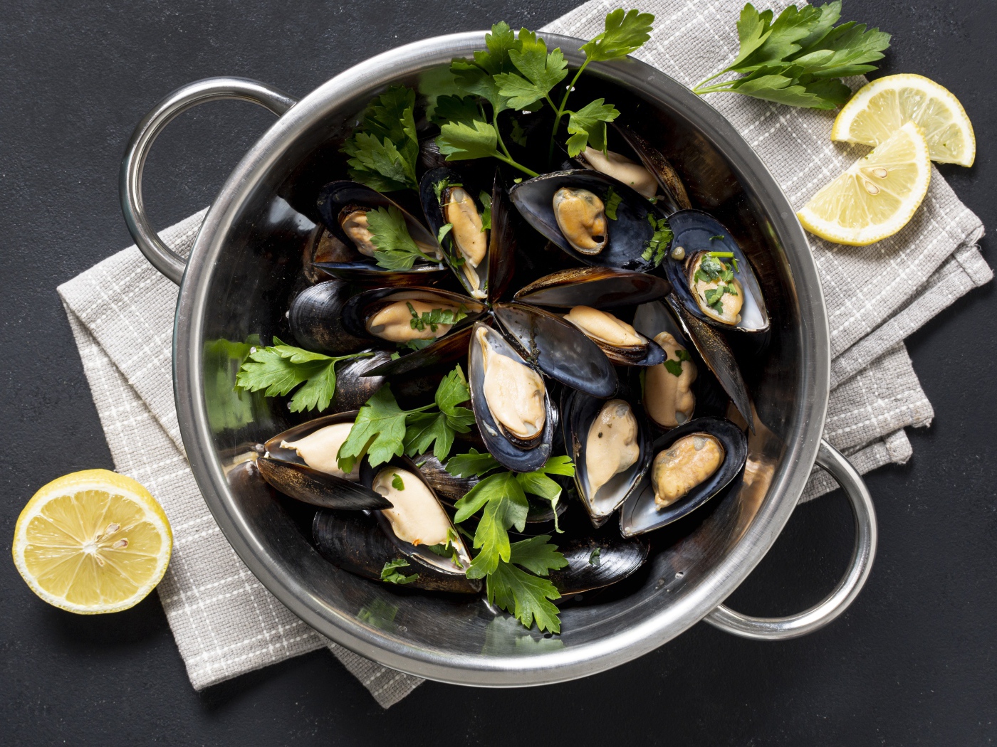 Свежие мидии в кастрюле с зеленью петрушки 