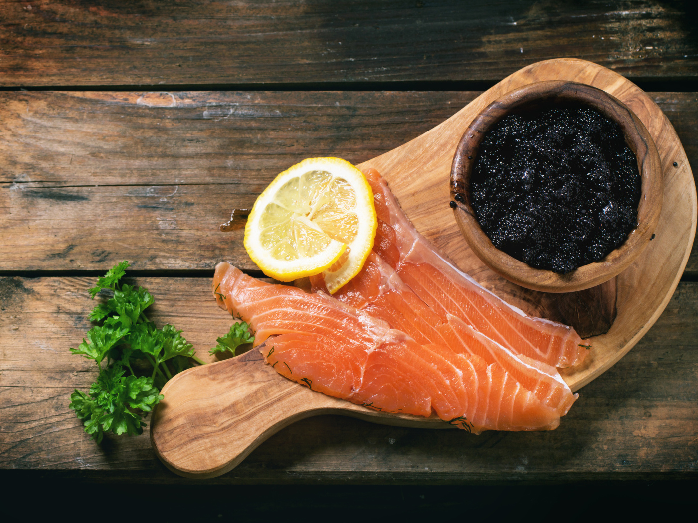 Slices of red fish with lemon on a table with black caviar