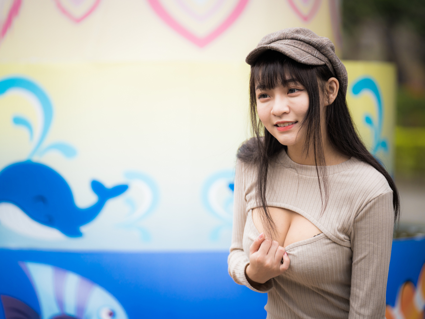 Улыбающаяся девушка азиатка стоит у стены  с рисунком