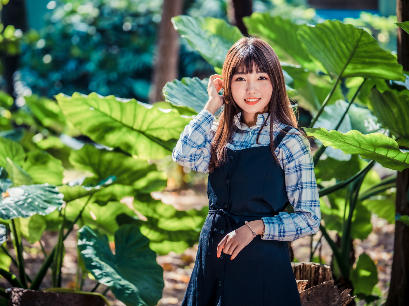 Улыбающаяся девушка азиатка в черном платье стоит в парке