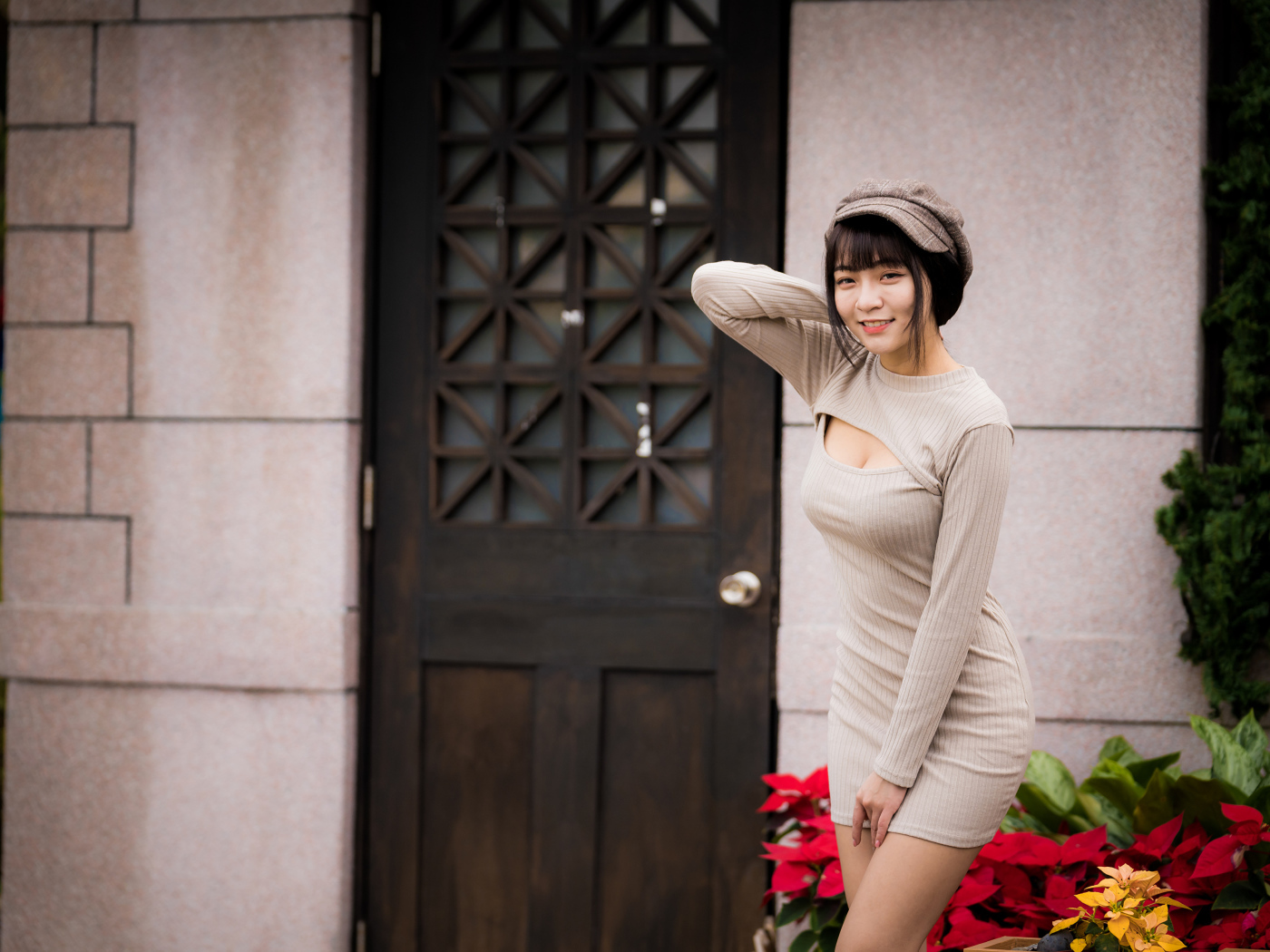 Красивая азиатка в платье стоит у двери 