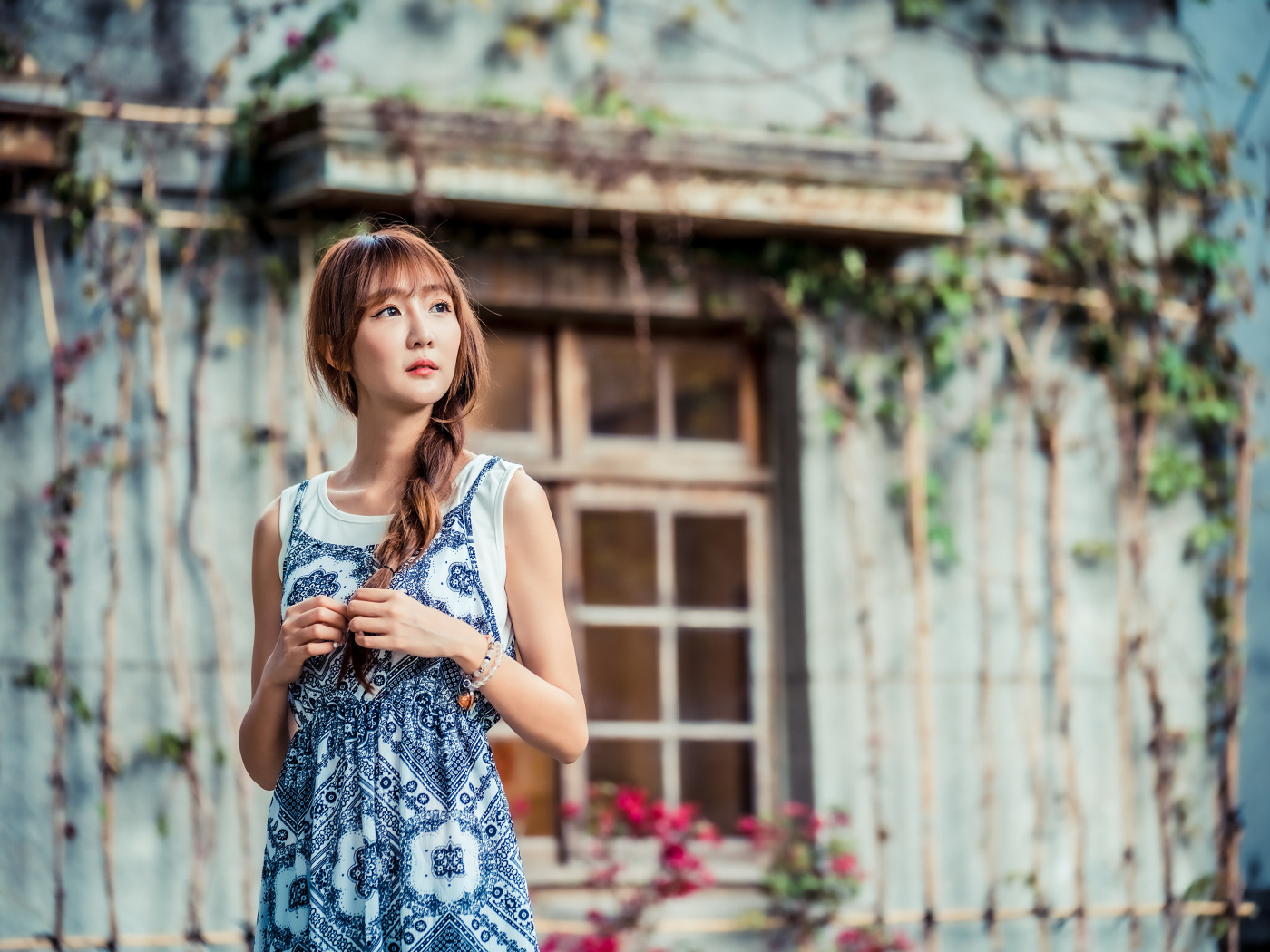 Красивая девушка азиатка в сарафане у старого дома 