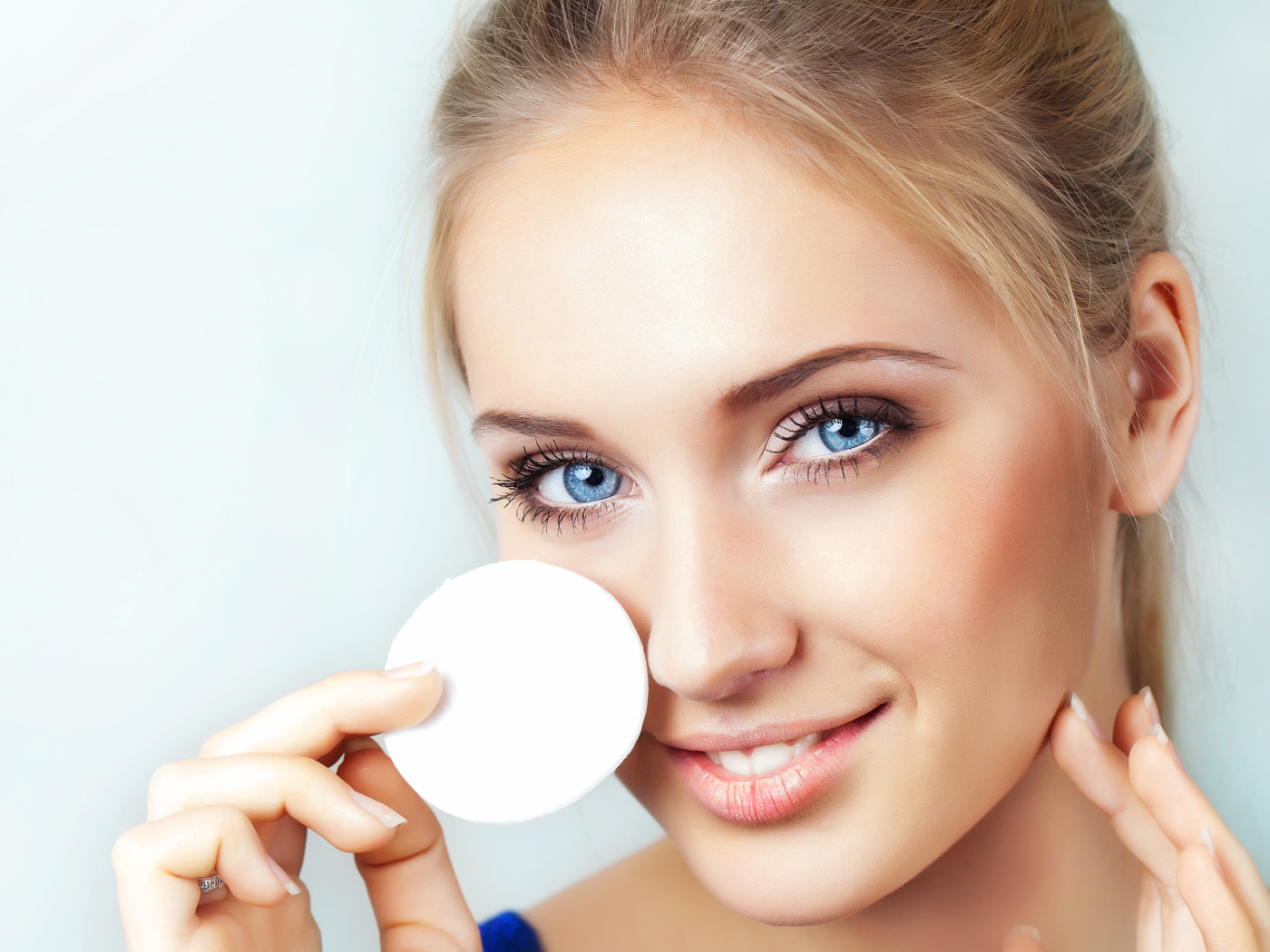 Красивая голубоглазая девушка с ватным диском в руке 