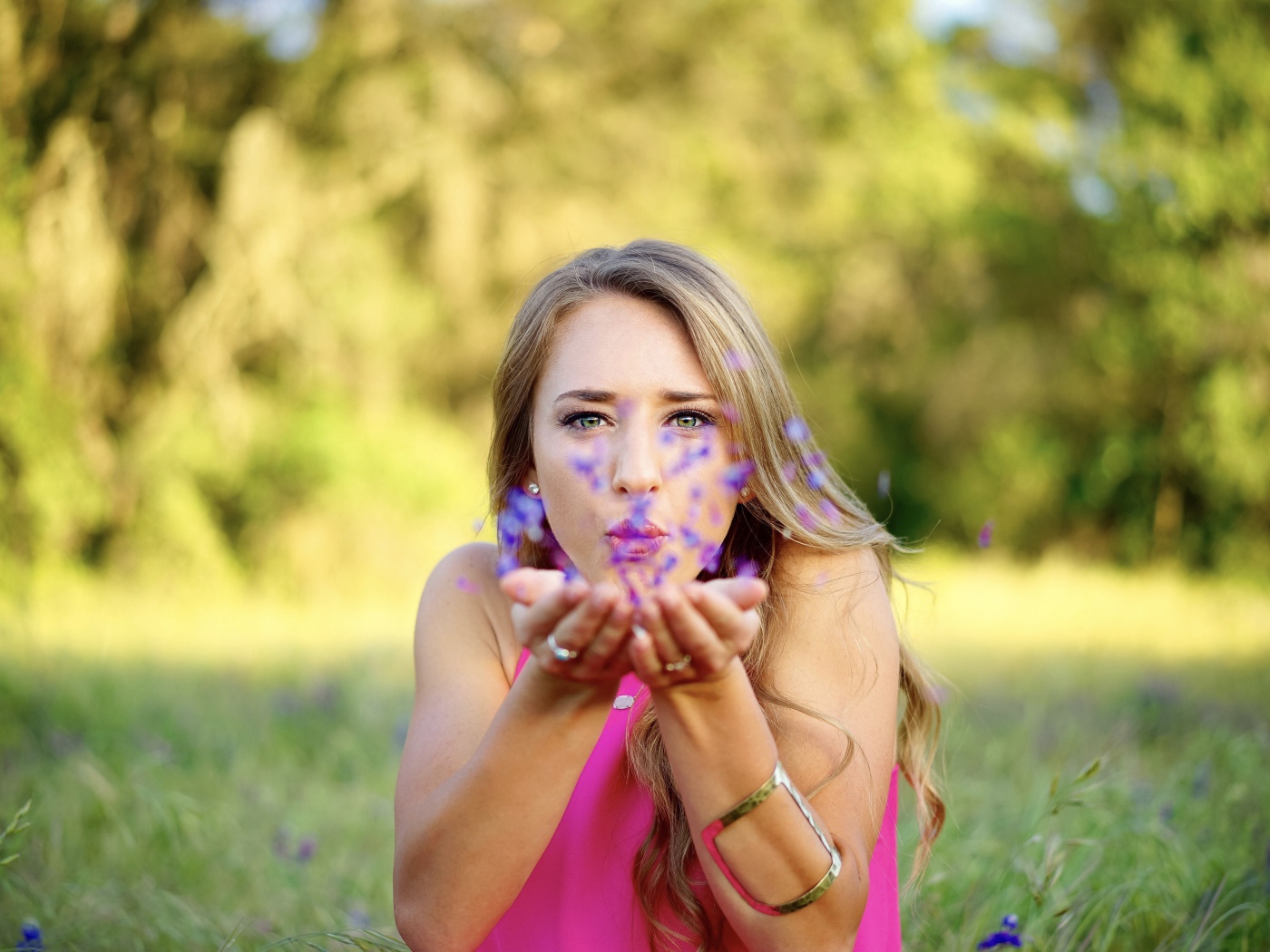 Красивая девушка сдувает лепестки с ладоней 