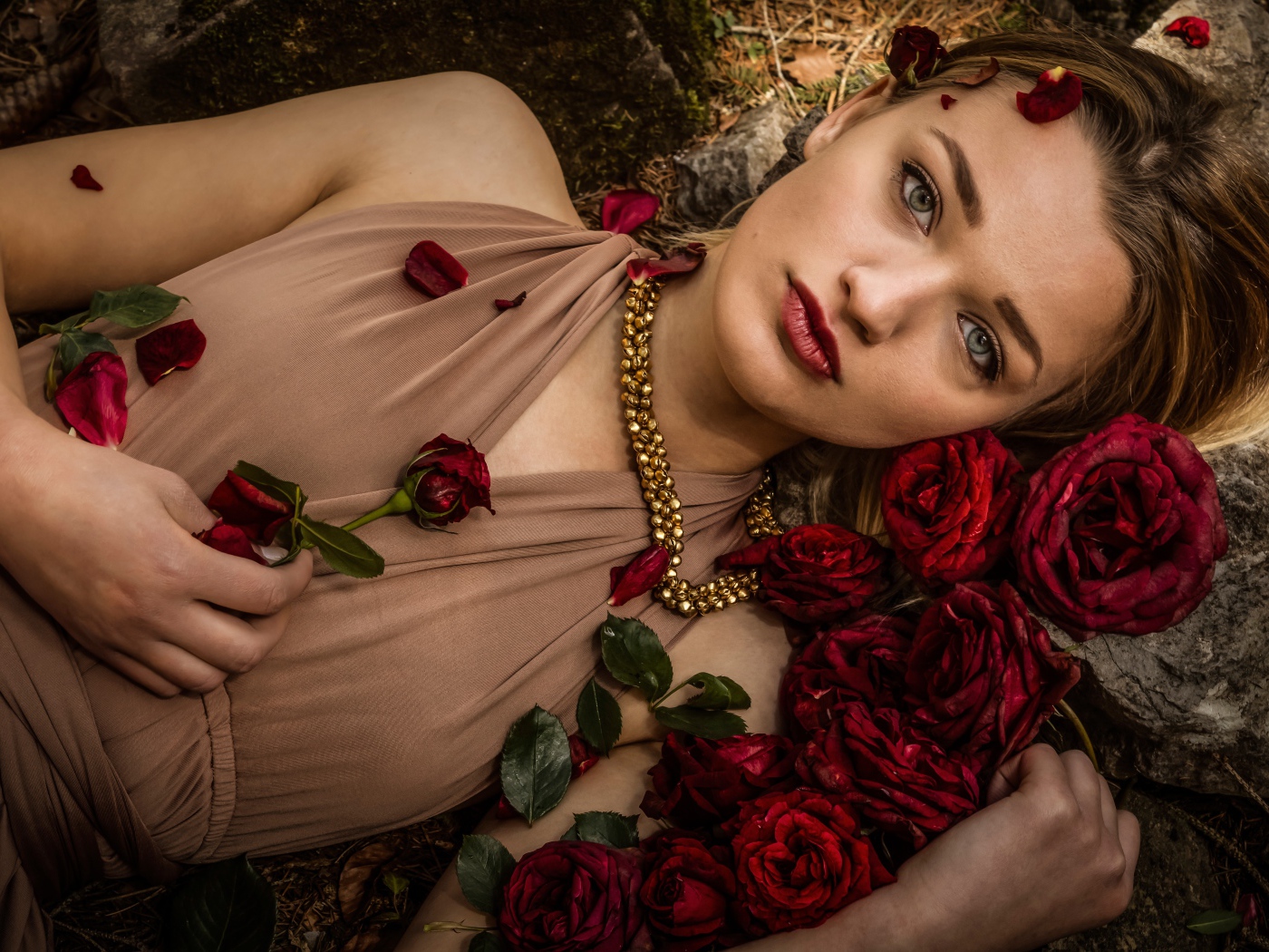 Красивая девушка в платье лежит на земле с розами