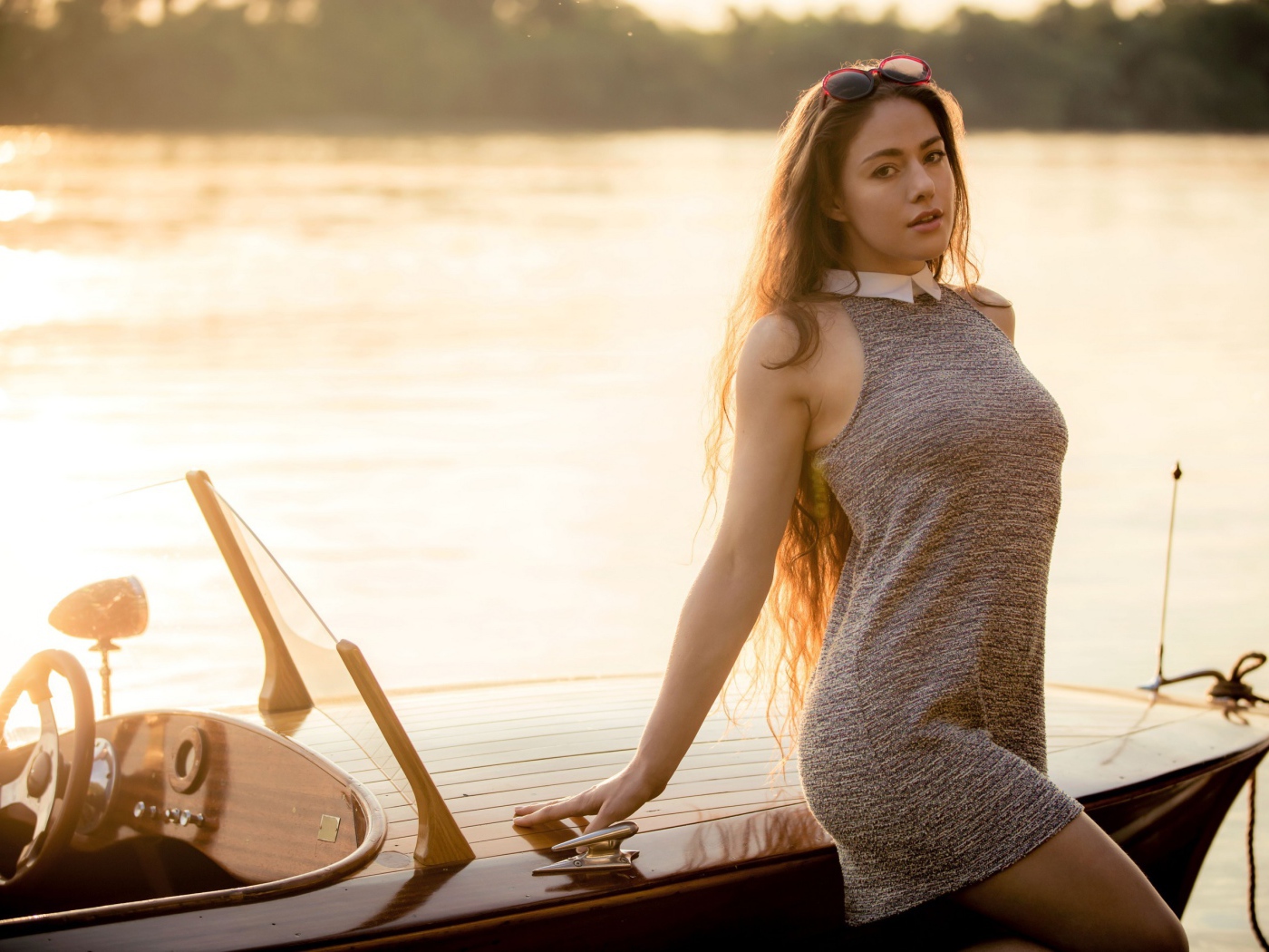 Красивая девушка в коротком платье стоит у катера 