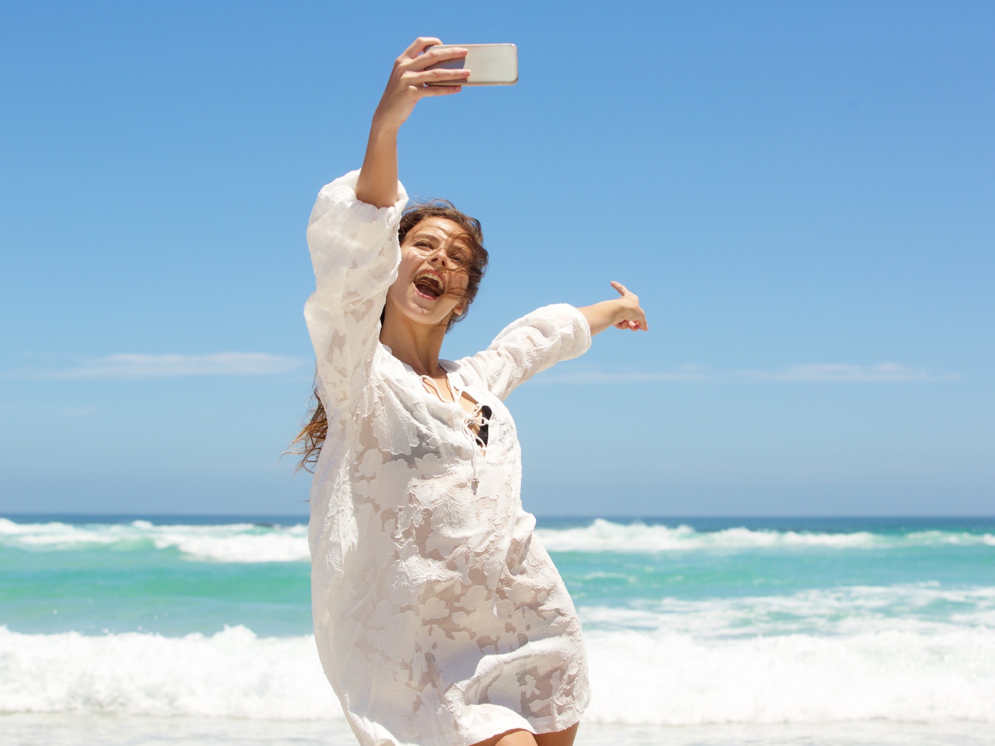 Красивая девушка в белом платье делает селфи на море 