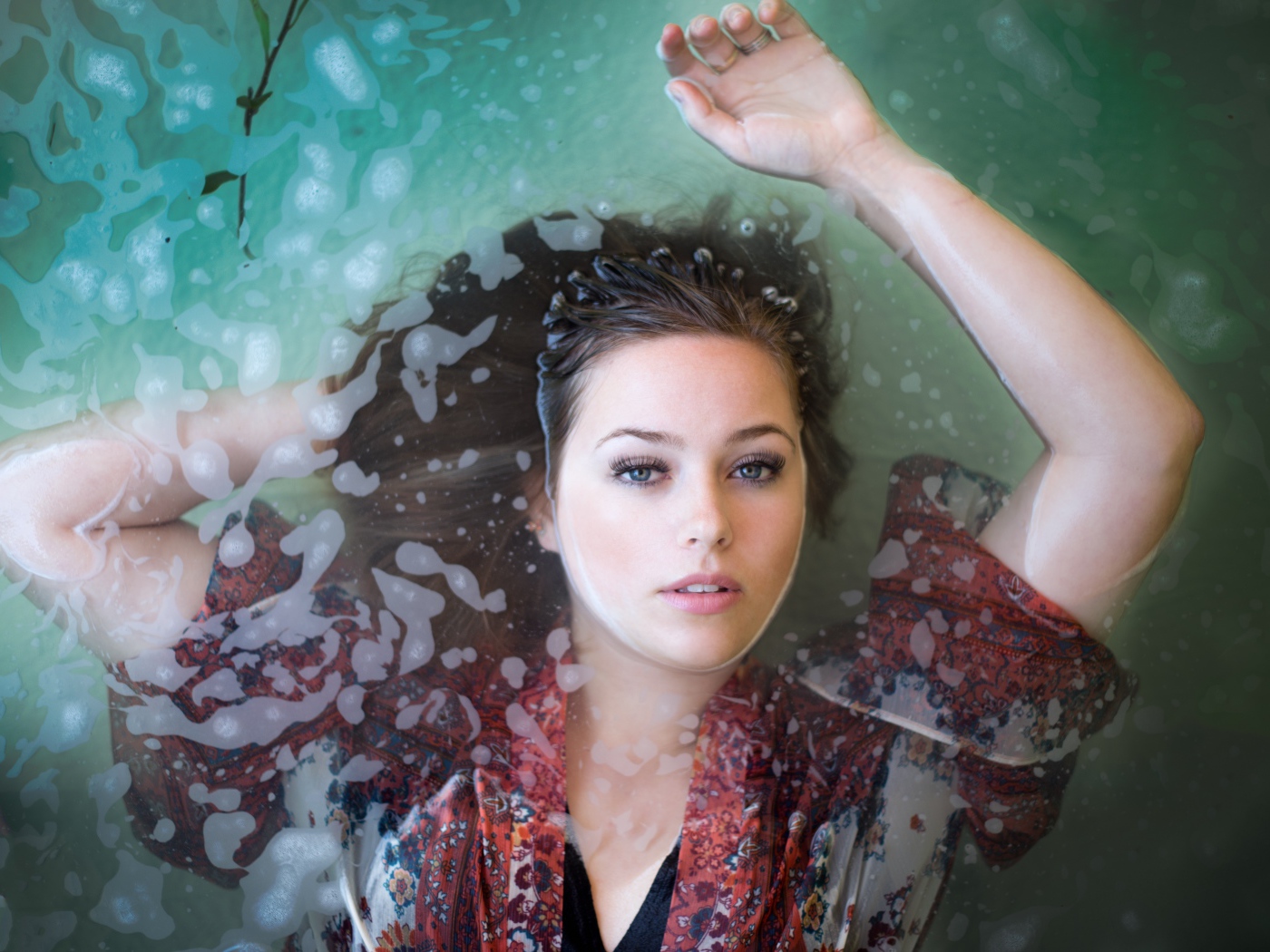 Красивая девушка лежит в одежде в воде 