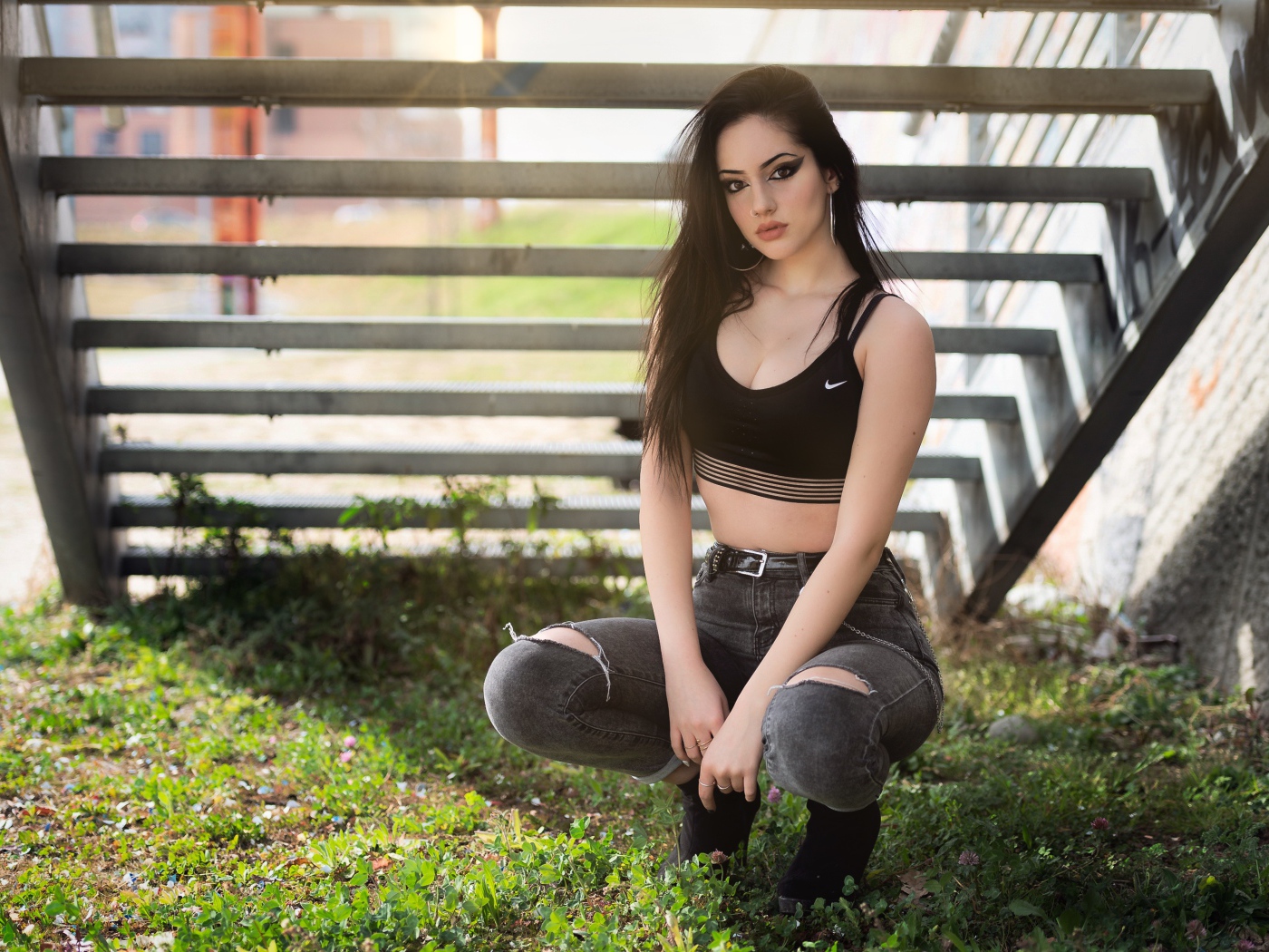 Красивая девушка сидит под лестницей 