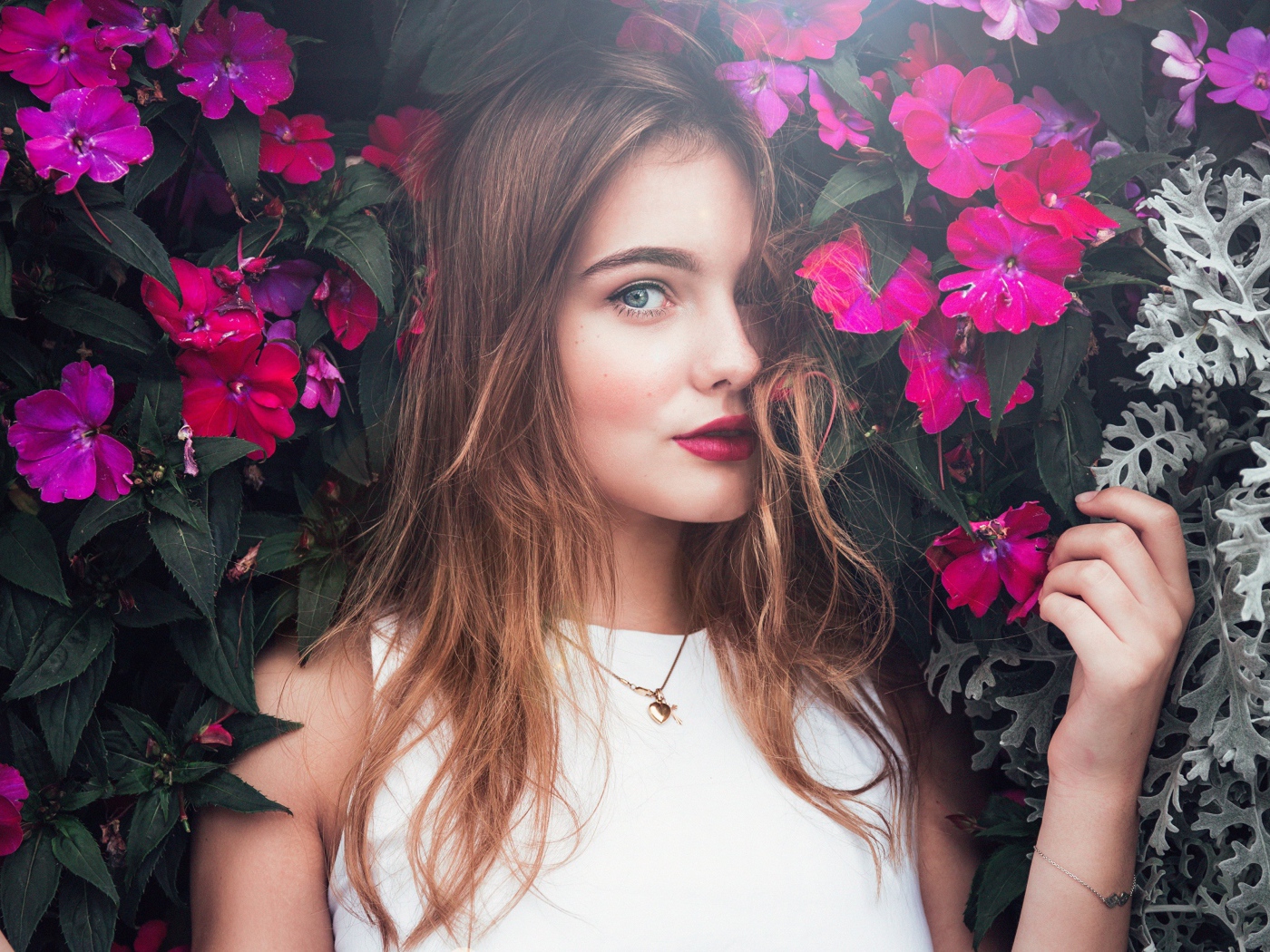 Красивая девушка стоит у зарослей с розовыми цветами