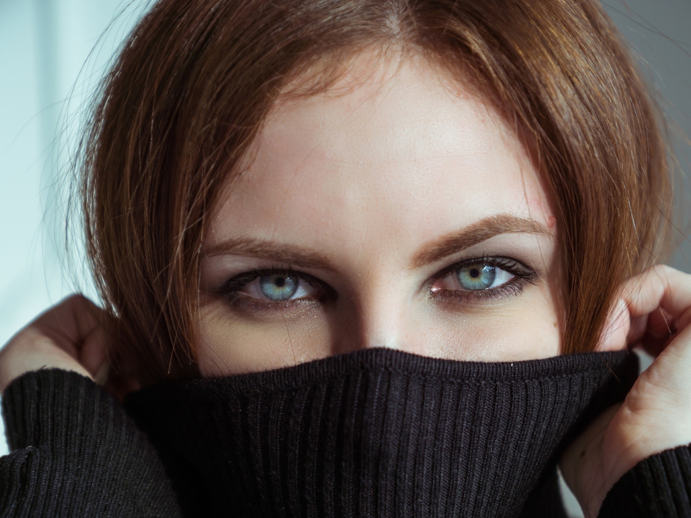 Красивая девушка с голубыми глазами закрыла лицо свитером 