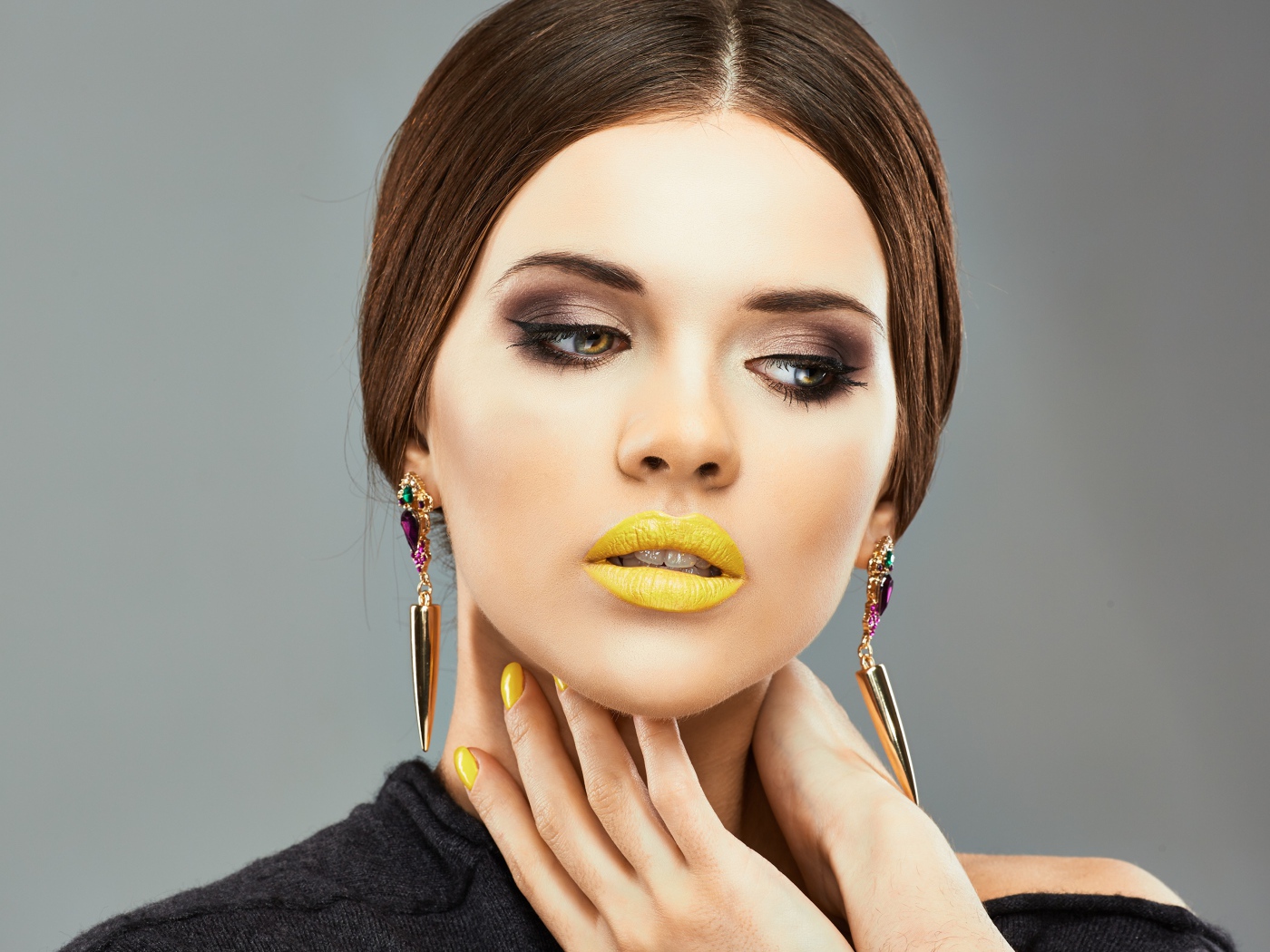 Красивая девушка с дорогими серьгами в ушах на сером фоне