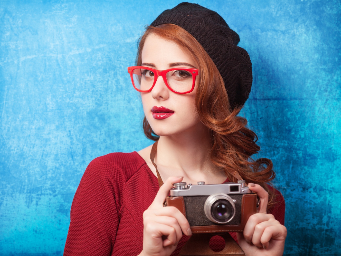 Красивая рыжеволосая девушка в черном берете с фотоаппаратом в руках 