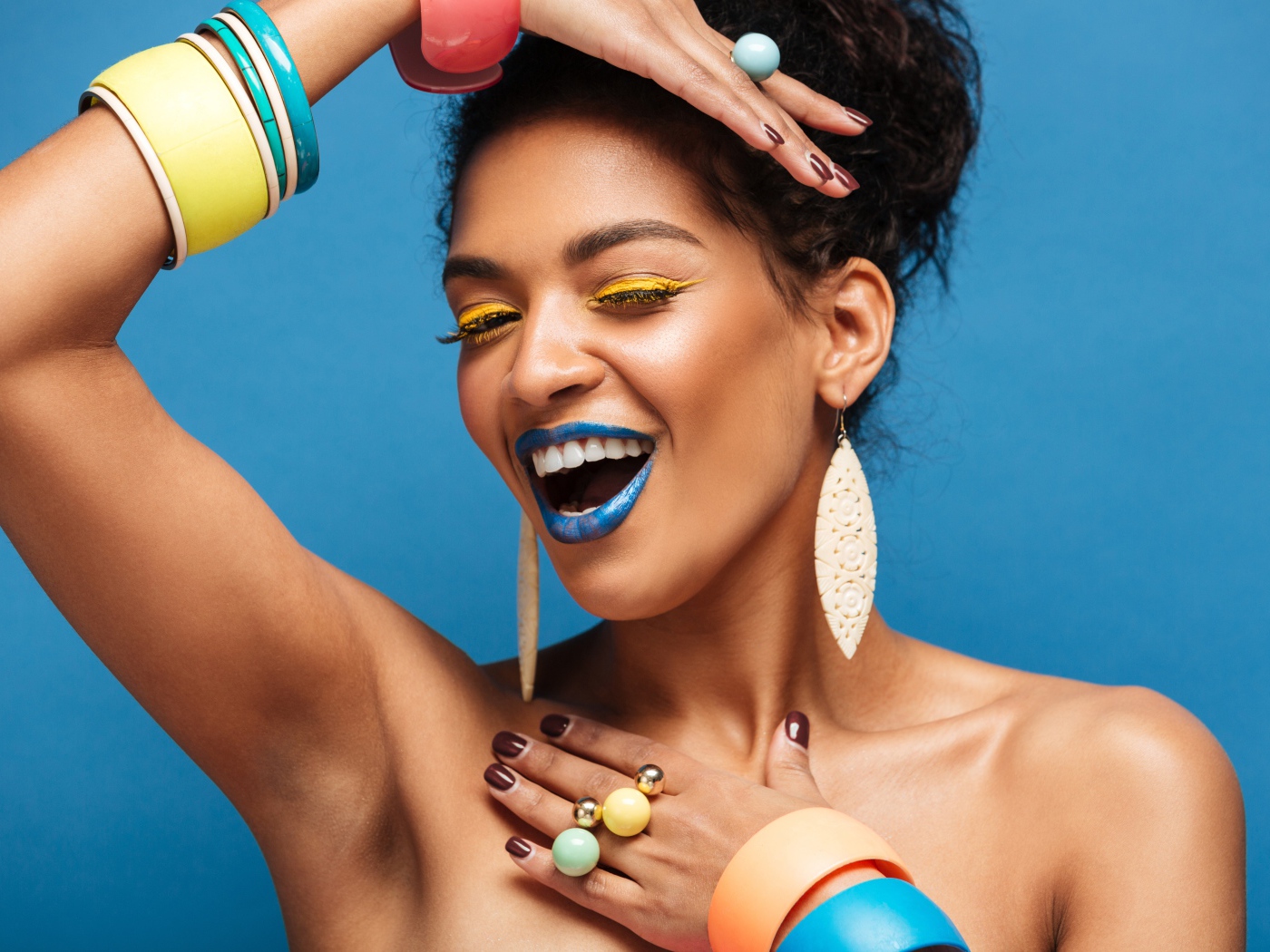 Красивая молодая девушка с ярким разноцветным макияжем на голубом фоне