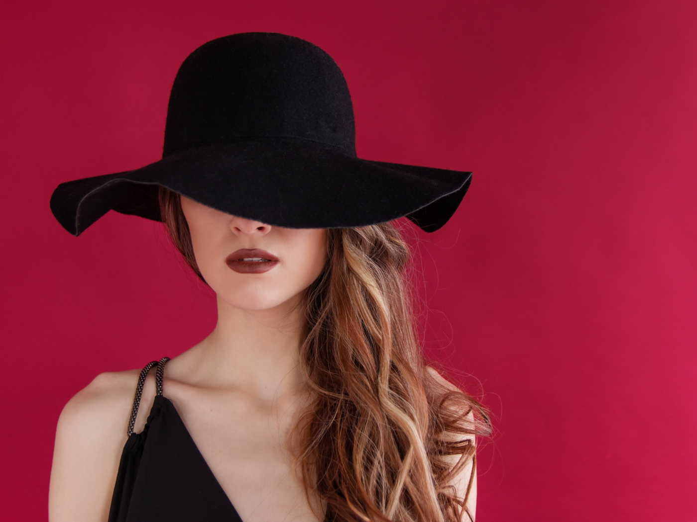 Большая черная шляпа закрывает лицо девушки