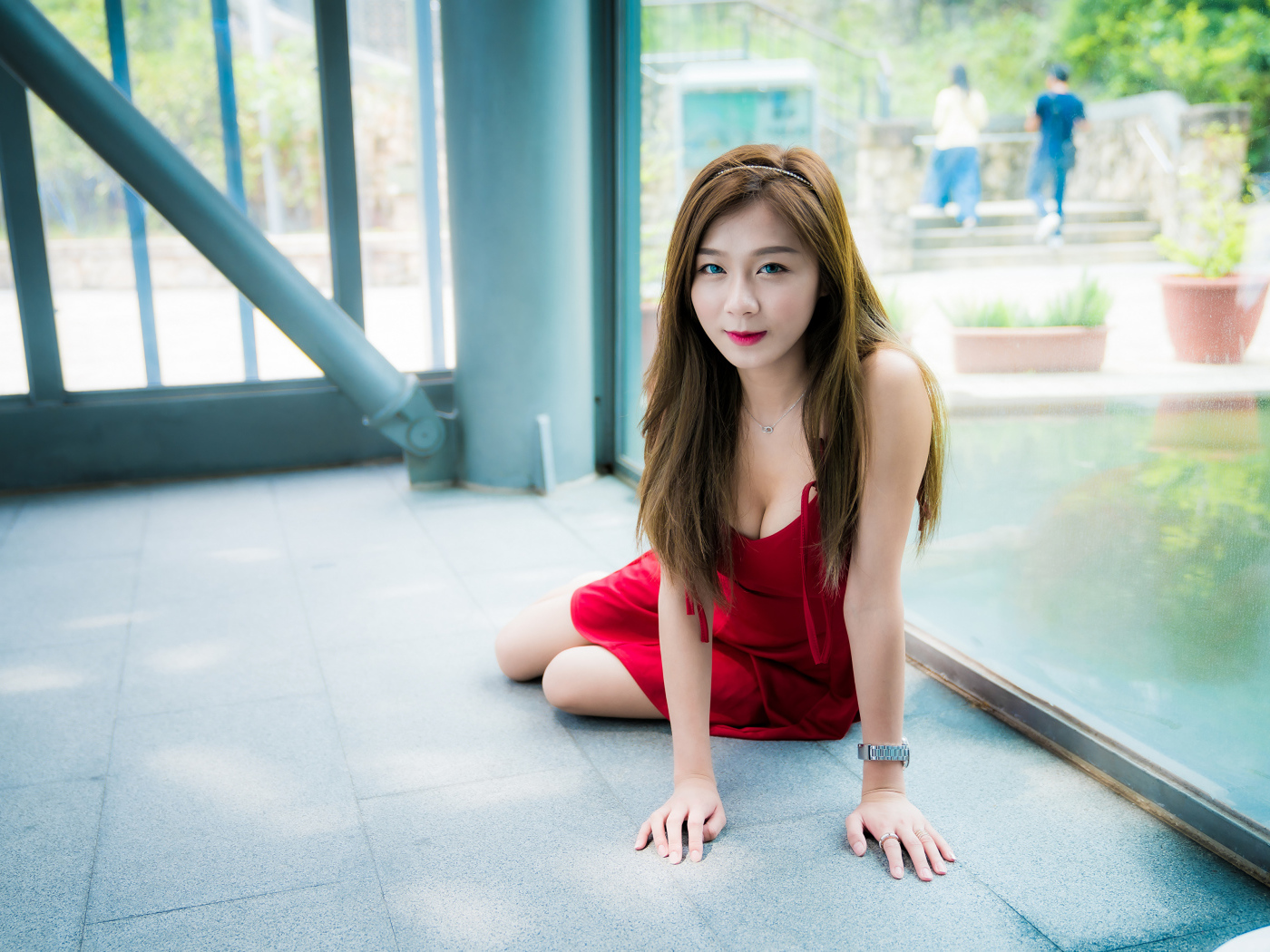 Голубоглазая девушка азиатка в красном платье на полу 